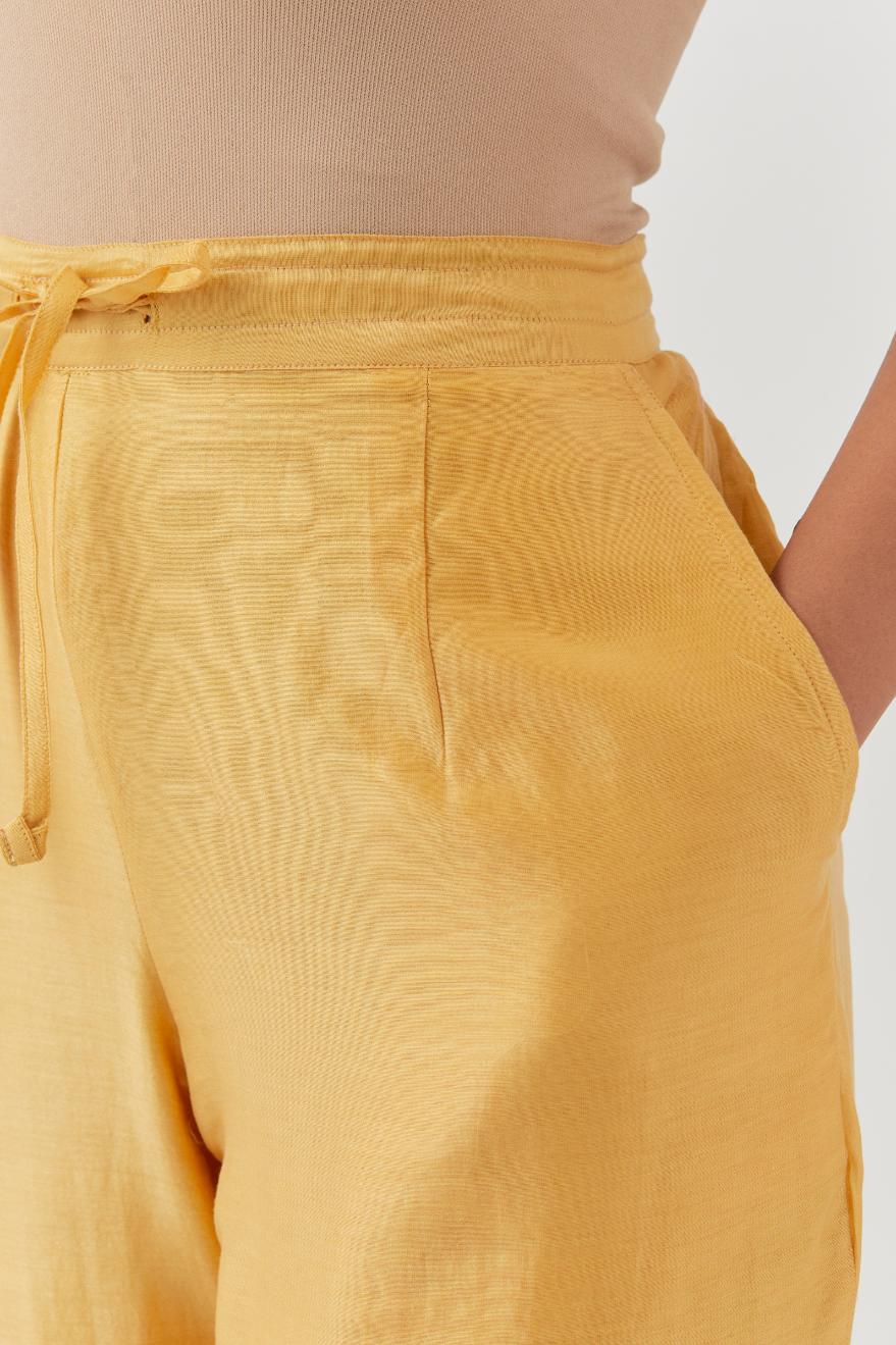 Yellow silk chanderi straight pants with a broad organza scalloped hem, highlighted with embroidered rose flower bunches and beads.