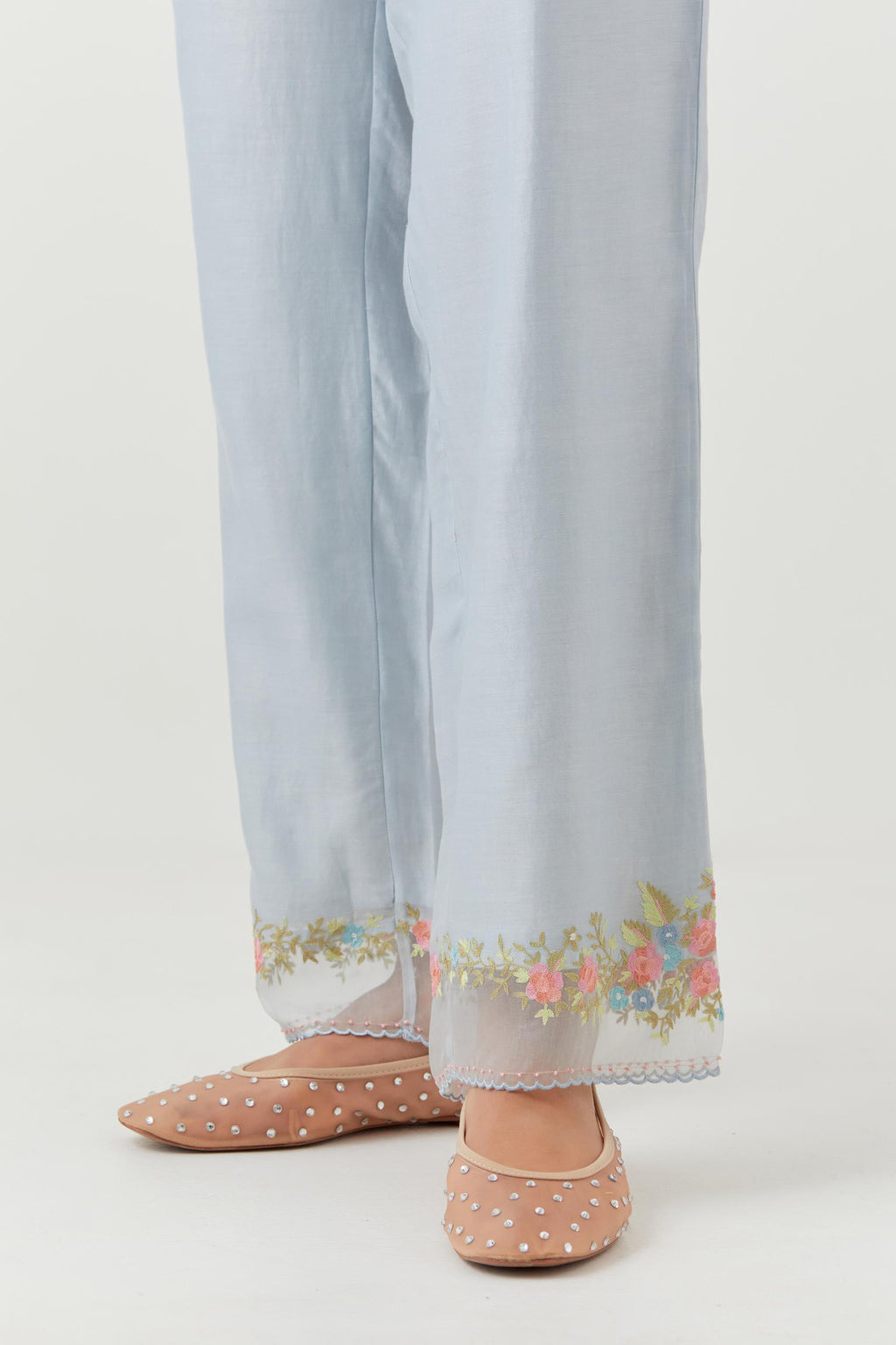 Blue silk chanderi straight pants with a broad organza scalloped hem, highlighted with embroidered rose flower bunches and beads.