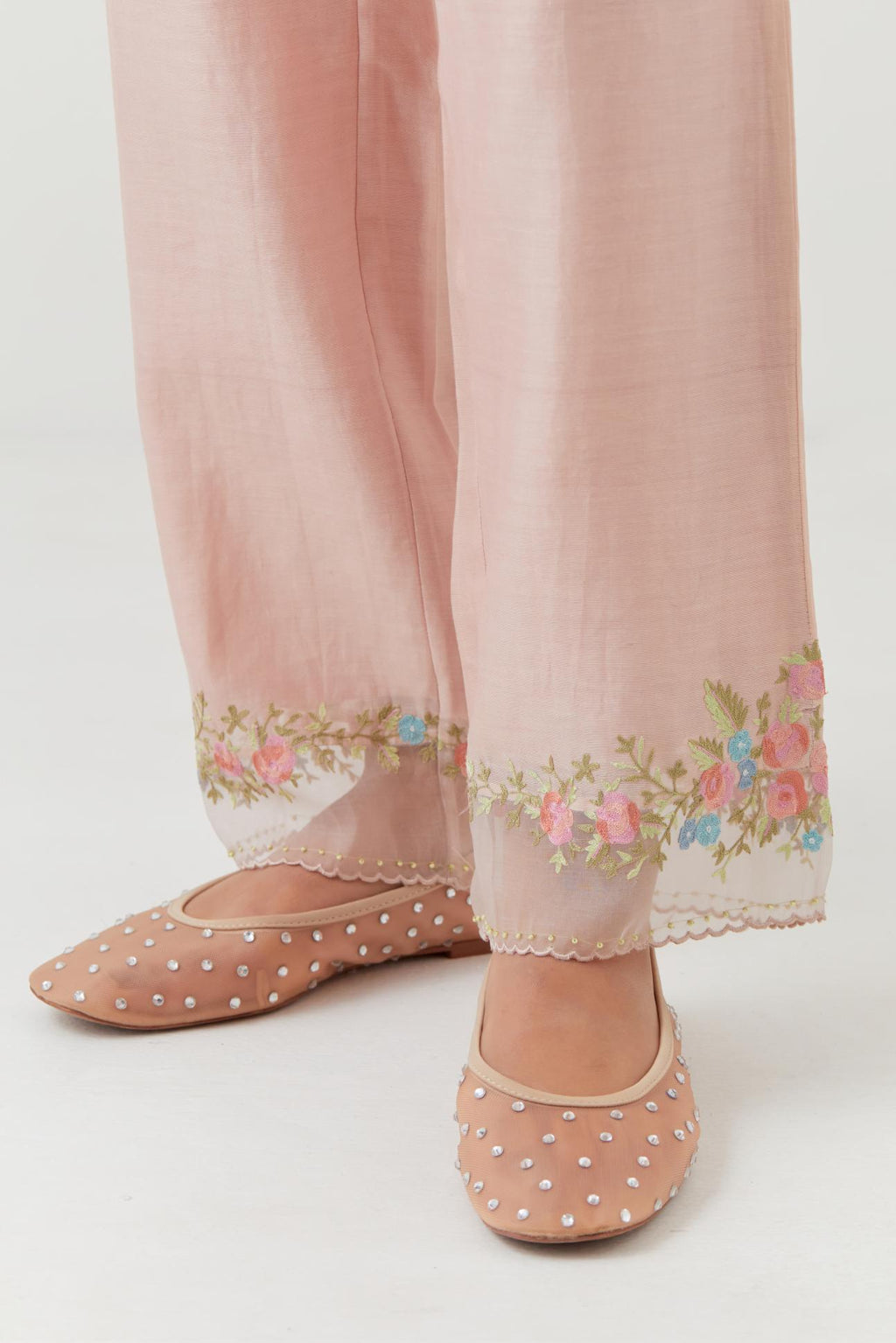 Pink silk chanderi straight pants with a broad organza scalloped hem, highlighted with embroidered rose flower bunches and beads.