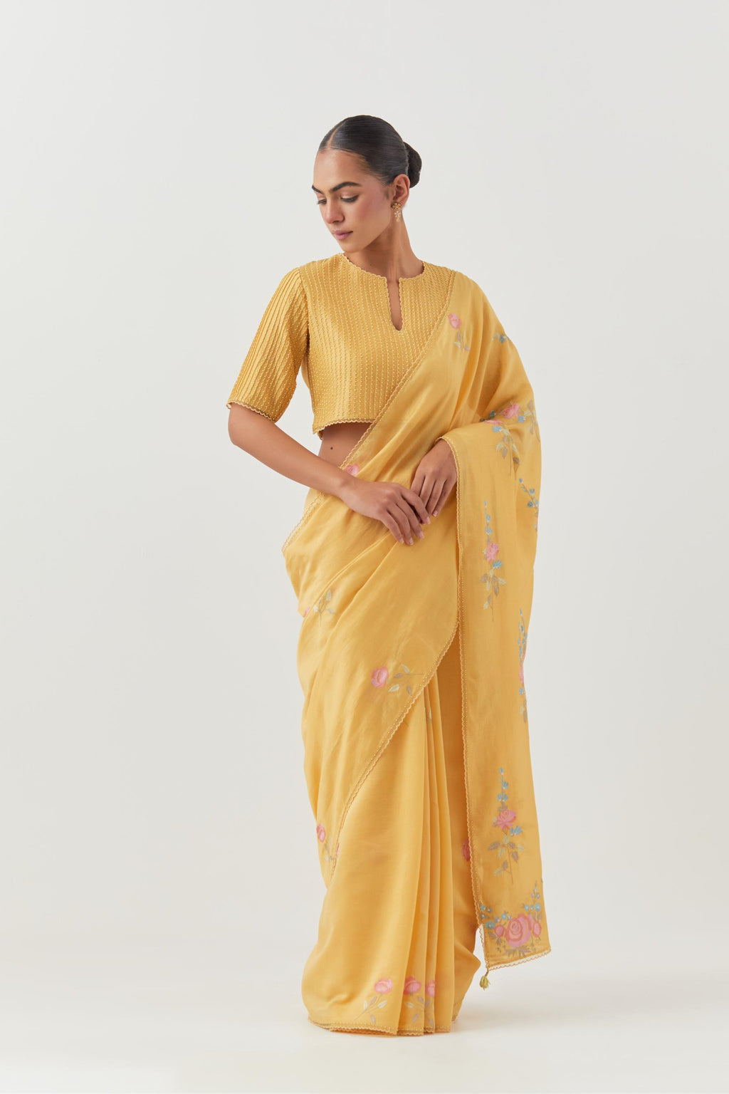 Yellow silk chanderi saree with all-over thread embroidered roses and scalloped organza with delicate bead detail at the edges, paired with yellow silk blouse with pin tucks, highlighted with bead work.