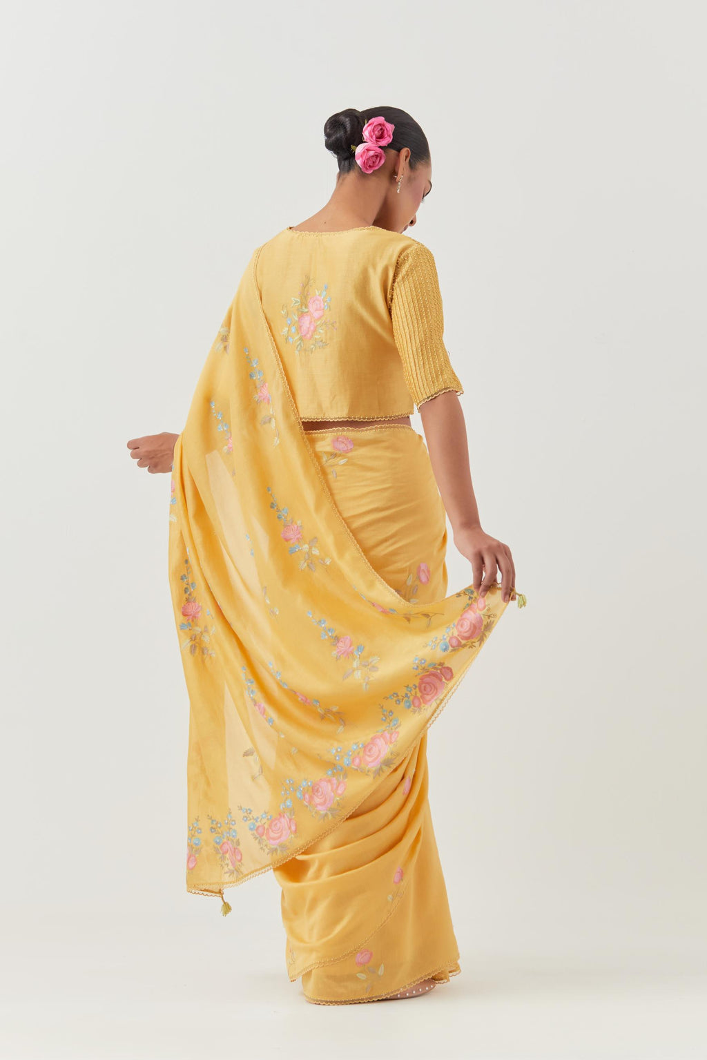 Yellow silk chanderi saree with all-over thread embroidered roses and scalloped organza with delicate bead detail at the edges, paired with yellow silk blouse with pin tucks, highlighted with bead work.