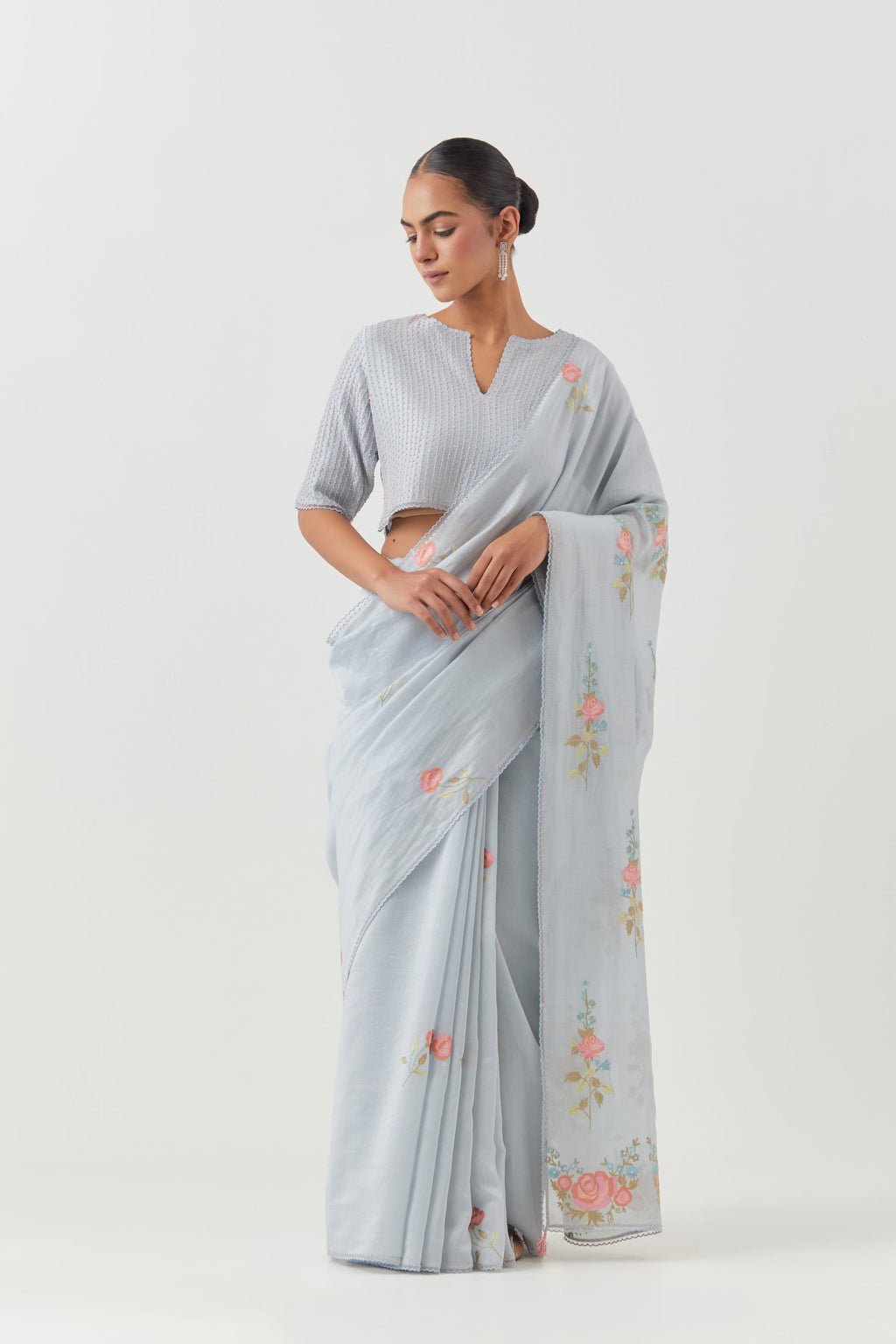 Blue silk chanderi saree with all-over thread embroidered roses and scalloped organza with delicate bead detail at the edges, paired with blue silk blouse with pin tucks, highlighted with bead work.