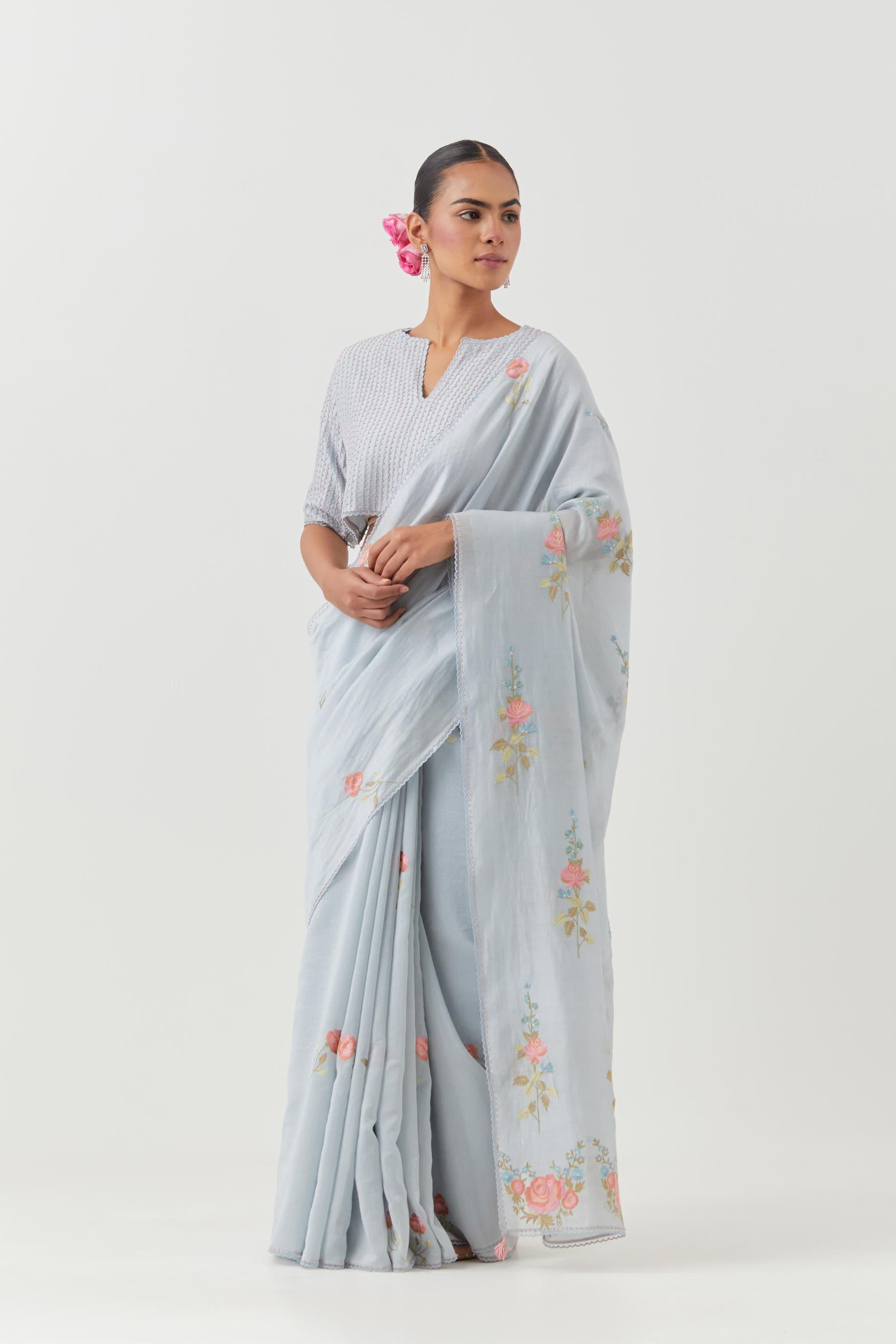 Blue silk chanderi saree with all-over thread embroidered roses and scalloped organza with delicate bead detail at the edges, paired with blue silk blouse with pin tucks, highlighted with bead work.
