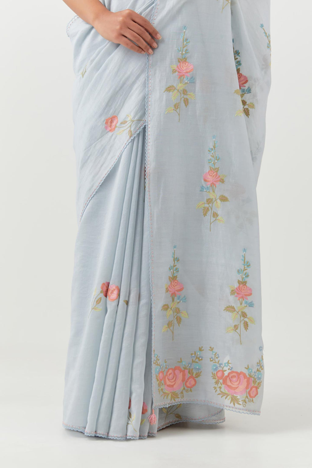 Blue silk chanderi saree with all-over thread embroidered roses and scalloped organza with delicate bead detail at the edges, paired with blue silk blouse with pin tucks, highlighted with bead work.