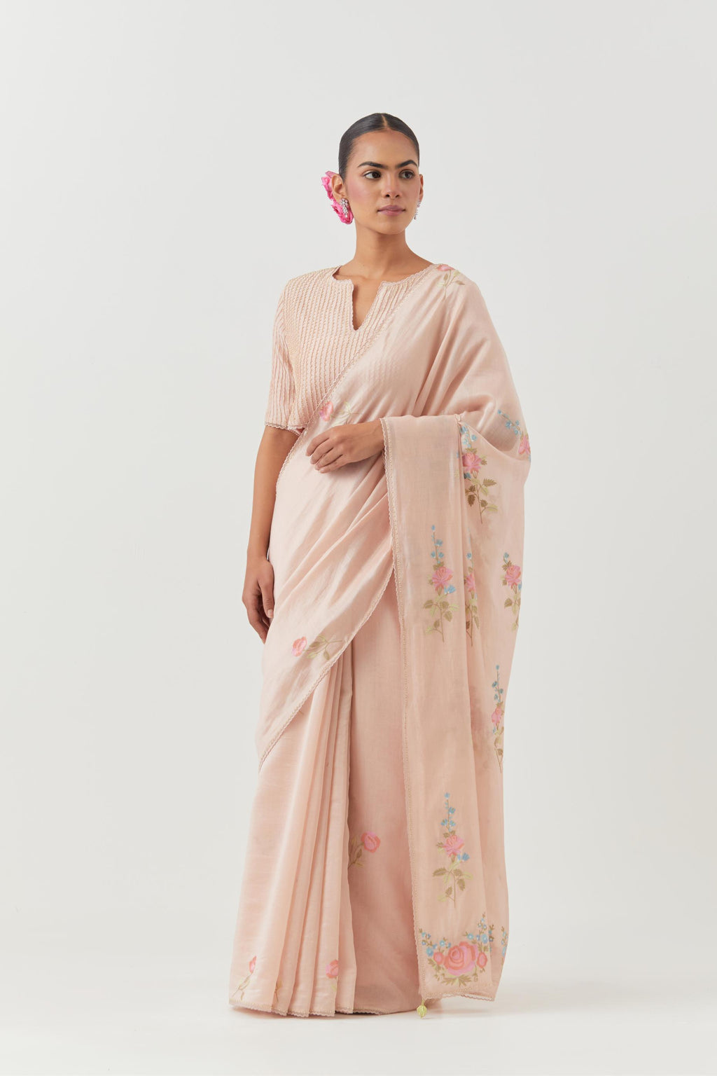 Pink silk chanderi saree with all-over thread embroidered roses and scalloped organza with delicate bead detail at the edges, paired with pink silk blouse with pin tucks, highlighted with bead work.