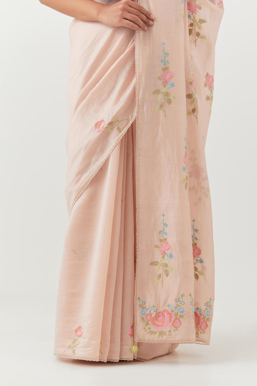 Pink silk chanderi saree with all-over thread embroidered roses and scalloped organza with delicate bead detail at the edges, paired with pink silk blouse with pin tucks, highlighted with bead work.