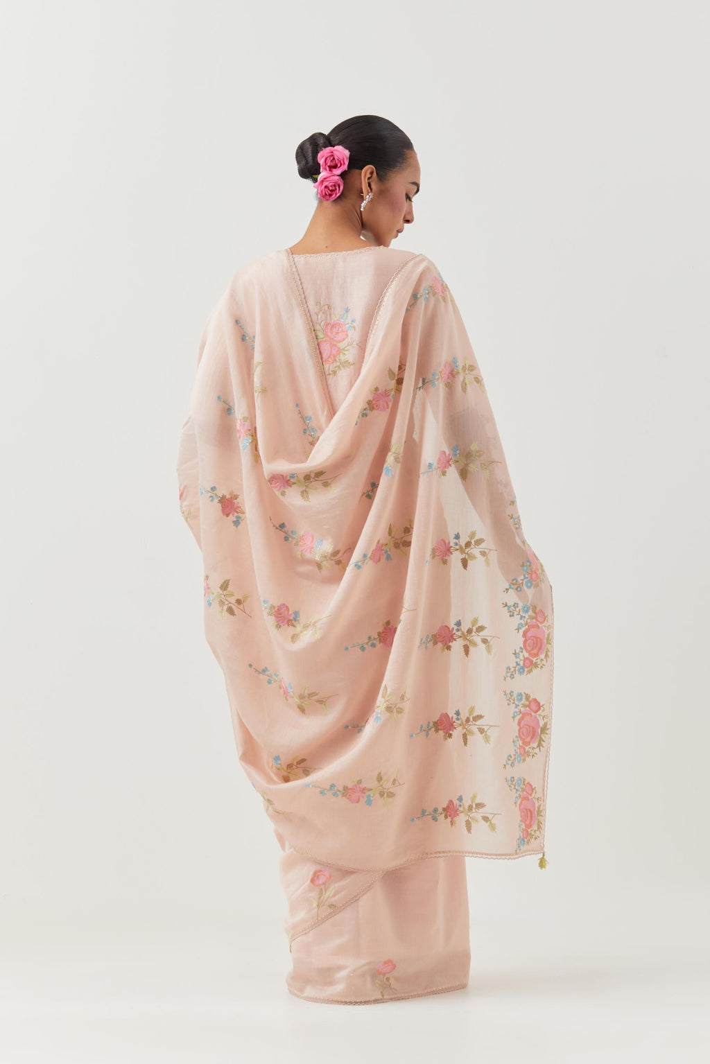 Pink silk chanderi saree with all-over thread embroidered roses and scalloped organza with delicate bead detail at the edges, paired with pink silk blouse with pin tucks, highlighted with bead work.