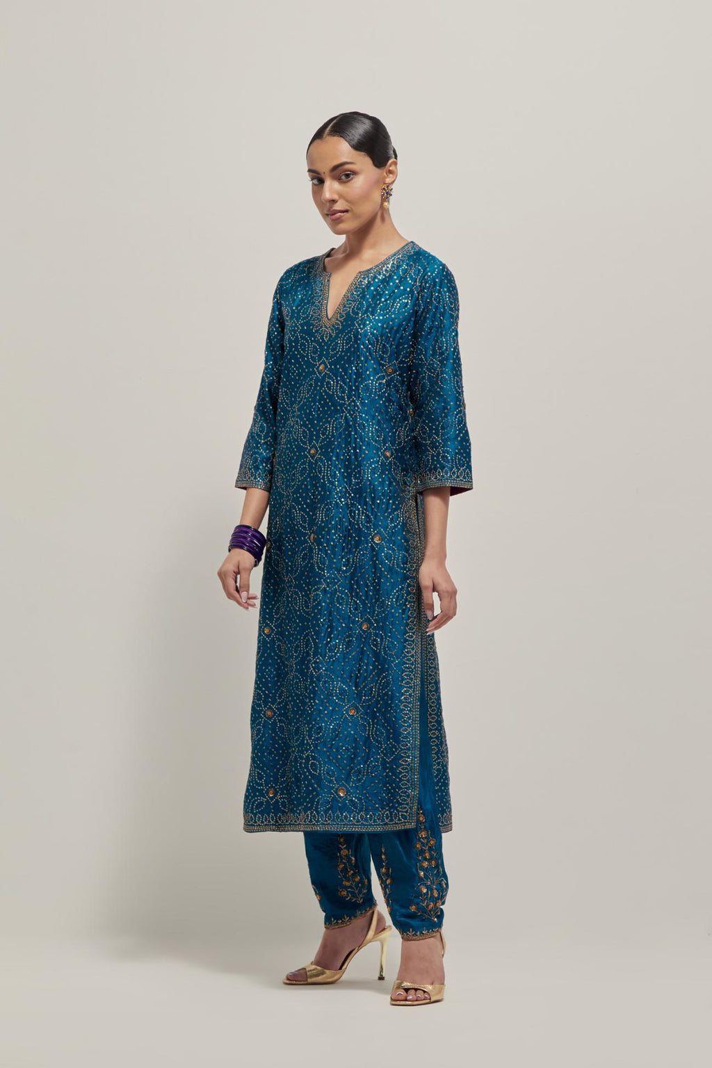 Teal silk straight kurta set with hand embroidered sequins on bandhani inspired jaal all-over the kurta, highlighted with contrast-colored beads.