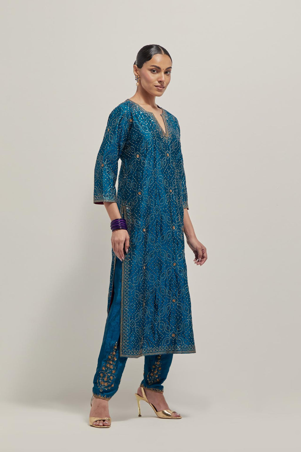 Teal silk straight kurta set with hand embroidered sequins on bandhani inspired jaal all-over the kurta, highlighted with contrast-colored beads.