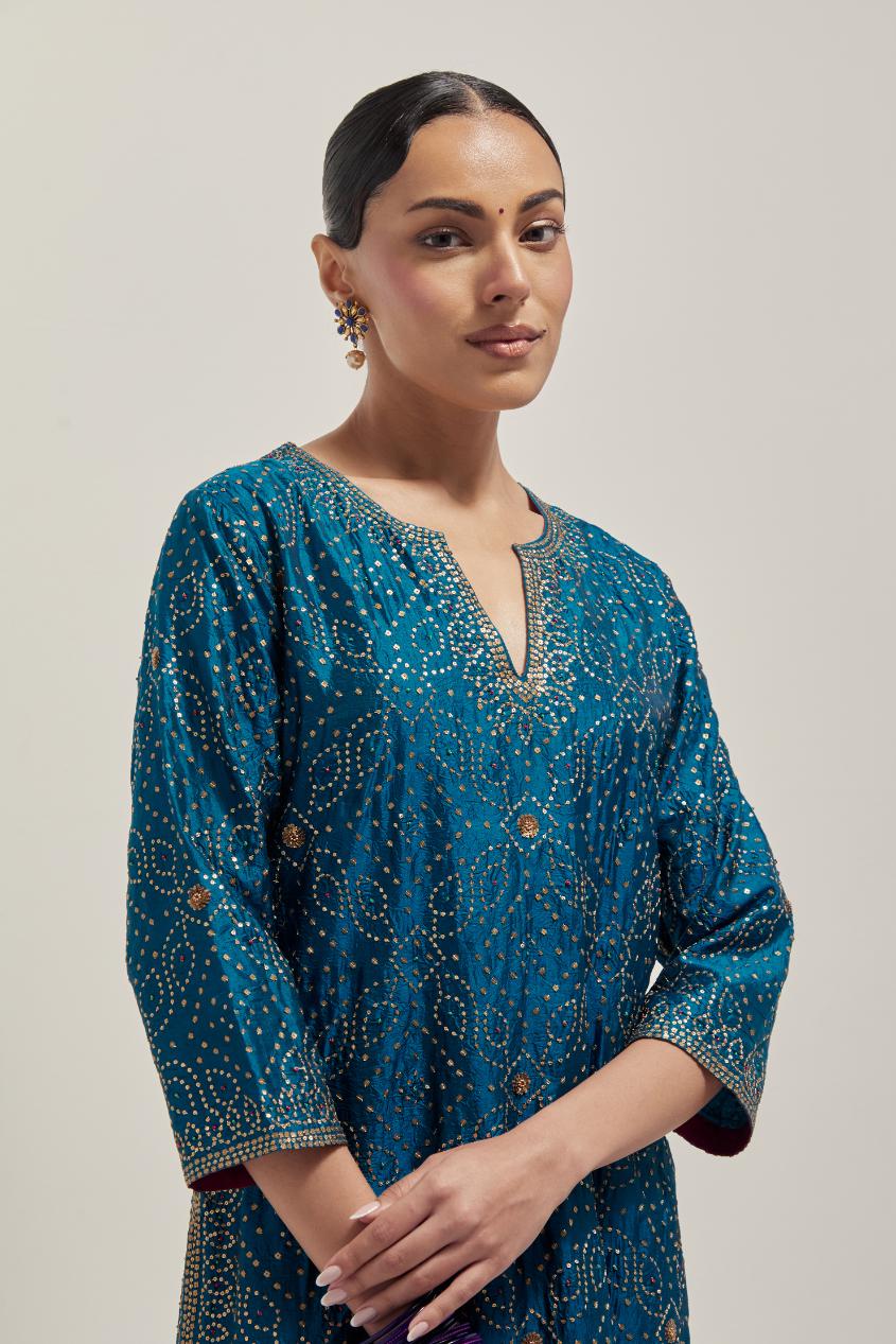 Teal silk straight kurta set with hand embroidered sequins on bandhani inspired jaal all-over the kurta, highlighted with contrast-colored beads.