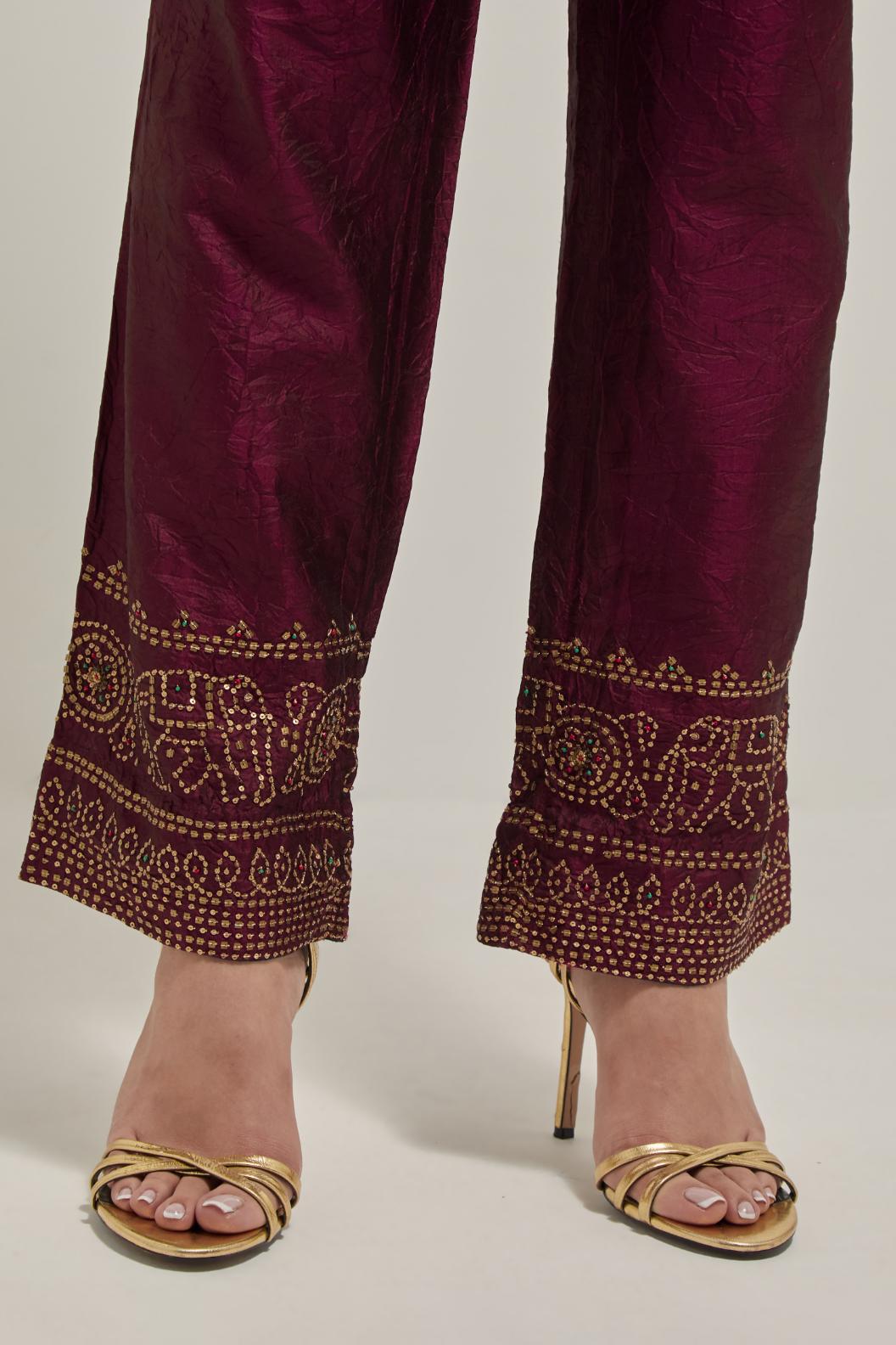 Maroon silk pants with a broad bandhani-inspired border at the hem, detailed with delicate bead and sequin work.