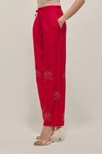Red silk pants with side pockets and assorted sequined elephants till mid-calf length.
