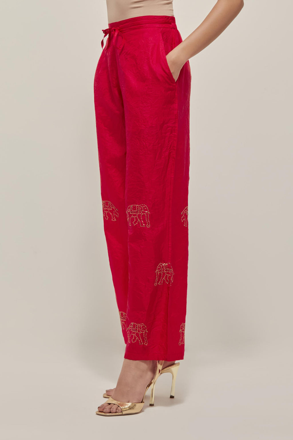 Red silk pants with side pockets and assorted sequined elephants till mid-calf length.