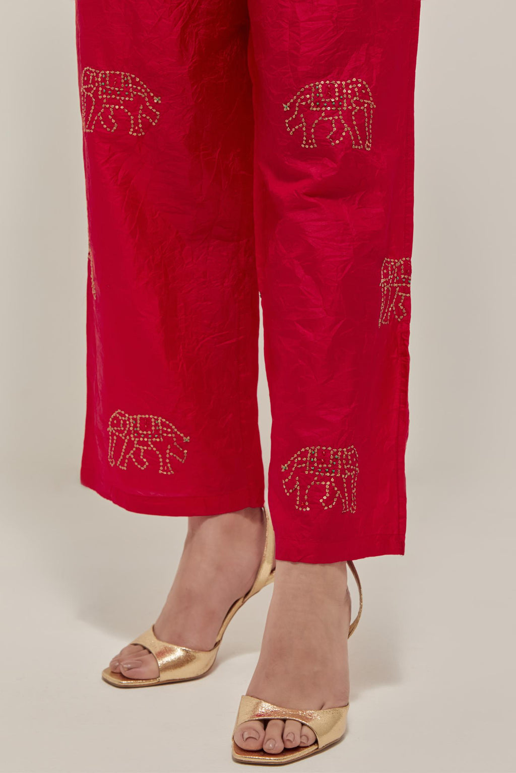 Red silk pants with side pockets and assorted sequined elephants till mid-calf length.