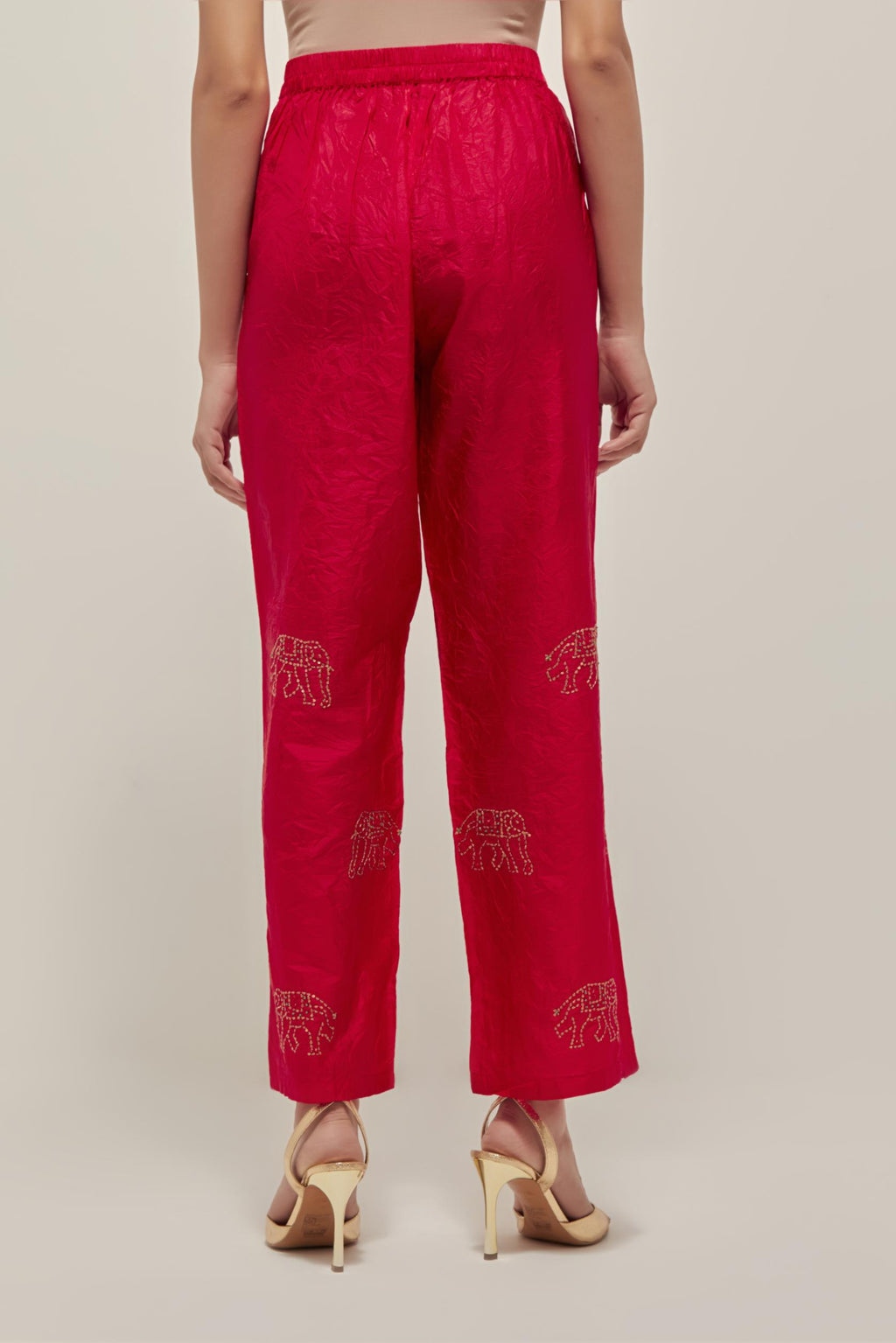 Red silk pants with side pockets and assorted sequined elephants till mid-calf length.