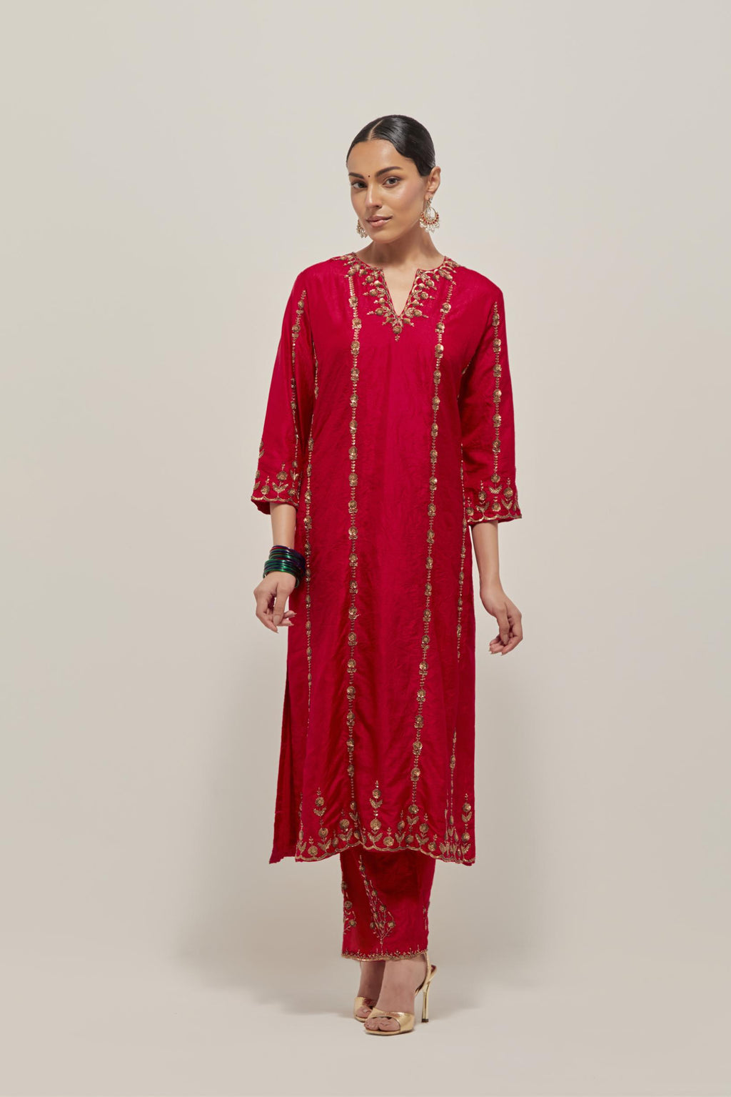 Red silk straight kurta set with round neck and slit in front. It has hand embroidered zardozi and sequins chhari stripes, all-over and heavier butas at hem, highlighted with beads.