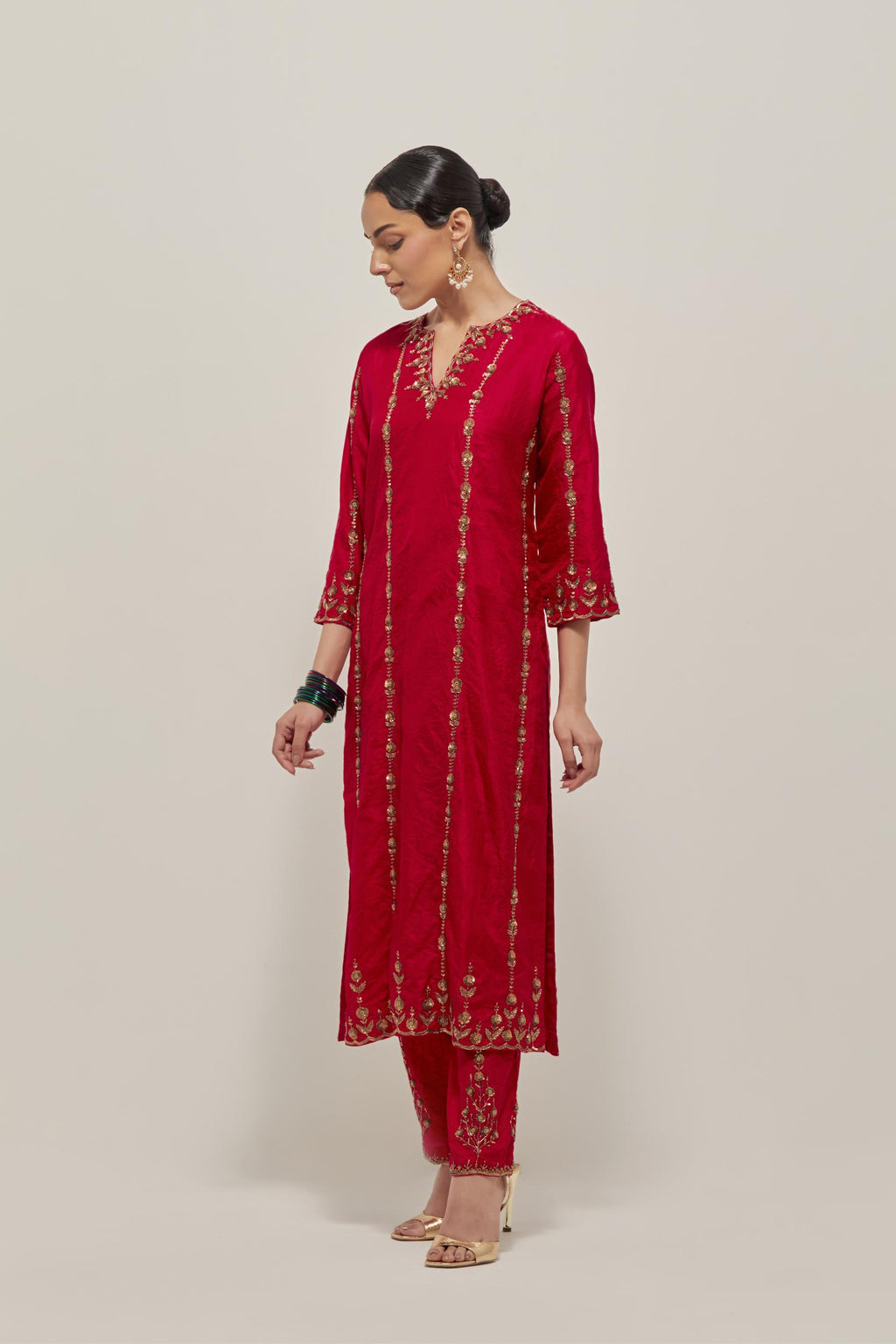 Red silk straight kurta set with round neck and slit in front. It has hand embroidered zardozi and sequins chhari stripes, all-over and heavier butas at hem, highlighted with beads.