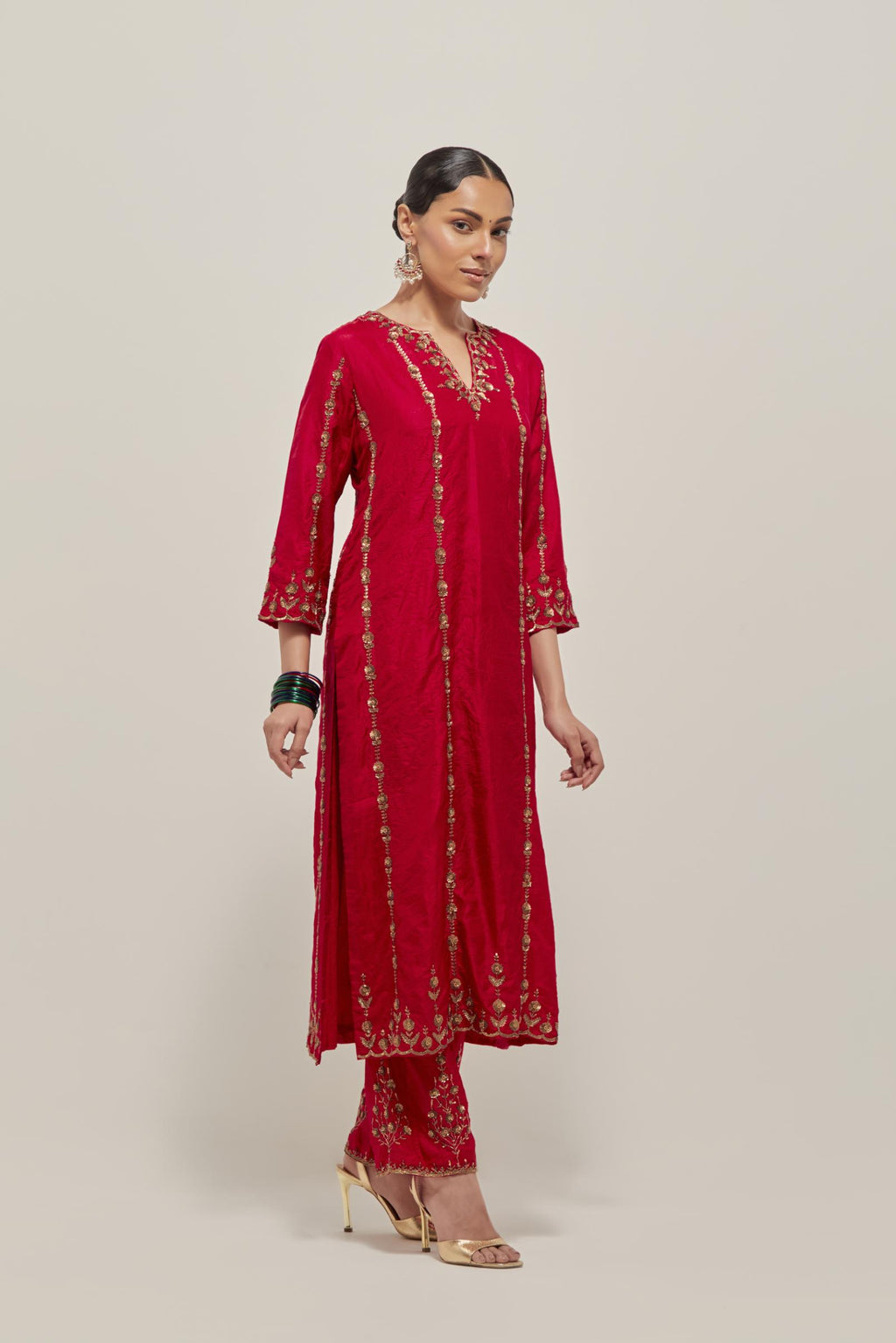 Red silk straight kurta set with round neck and slit in front. It has hand embroidered zardozi and sequins chhari stripes, all-over and heavier butas at hem, highlighted with beads.