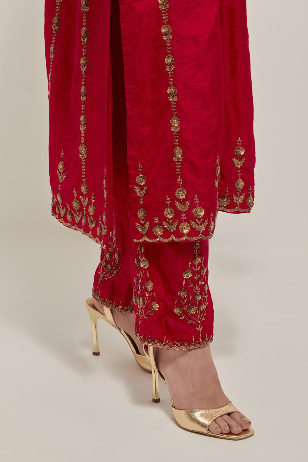 Red silk straight kurta set with round neck and slit in front. It has hand embroidered zardozi and sequins chhari stripes, all-over and heavier butas at hem, highlighted with beads.