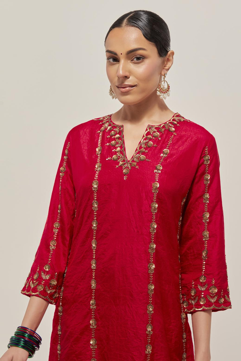 Red silk straight kurta set with round neck and slit in front. It has hand embroidered zardozi and sequins chhari stripes, all-over and heavier butas at hem, highlighted with beads.