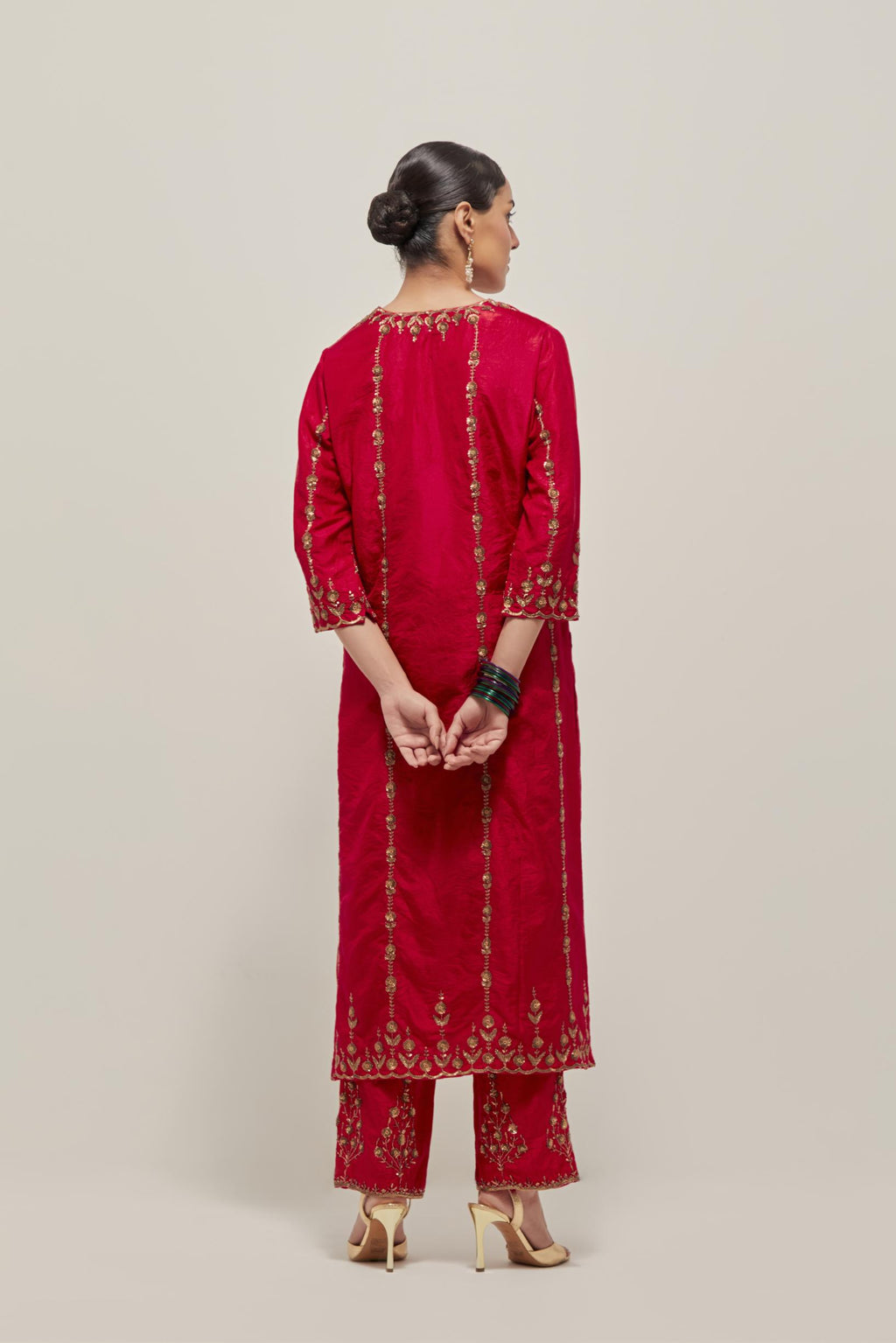 Red silk straight kurta set with round neck and slit in front. It has hand embroidered zardozi and sequins chhari stripes, all-over and heavier butas at hem, highlighted with beads.