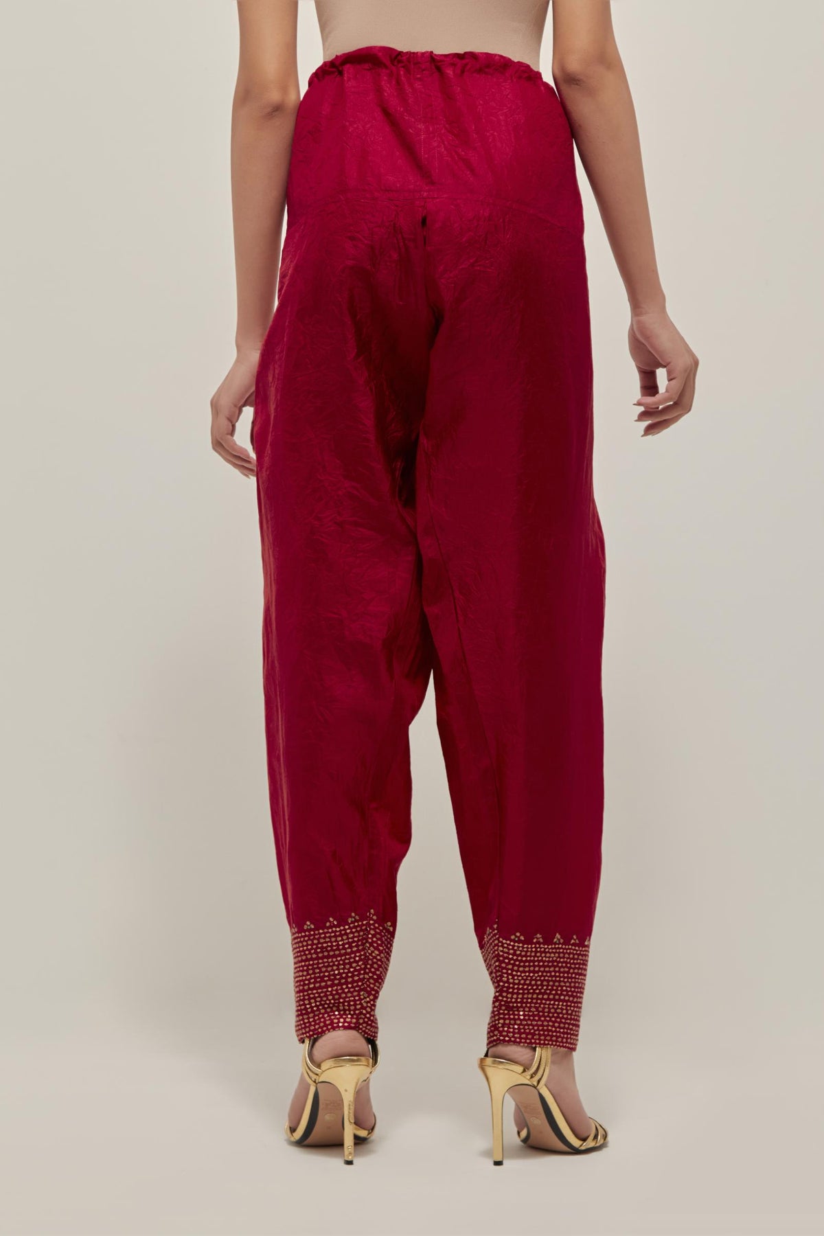 Red silk narrow salwar with a broad bandhani-inspired border at the hem, detailed with delicate bead and sequin work.