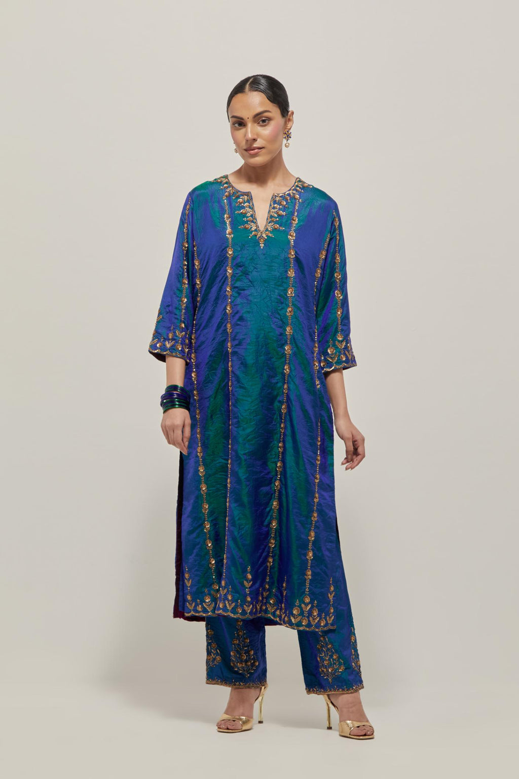 Teal Blue silk straight kurta set with round neck and slit in front. It has hand embroidered zardozi and sequins chhari stripes, all-over and heavier butas at hem, highlighted with beads.
