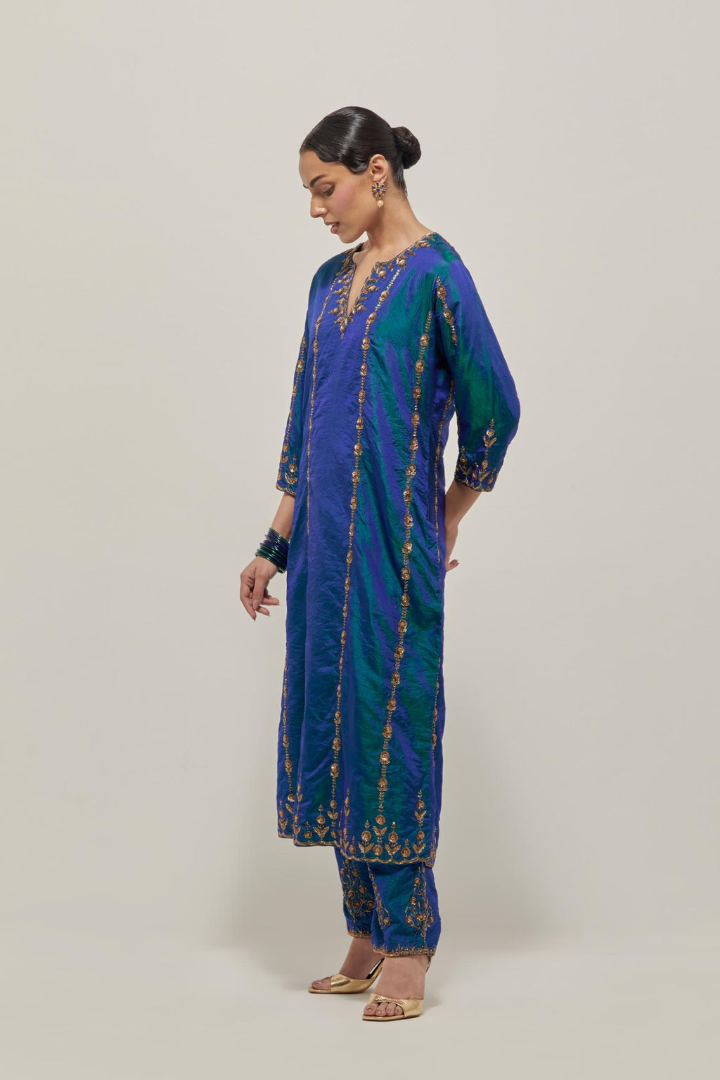 Teal Blue silk straight kurta set with round neck and slit in front. It has hand embroidered zardozi and sequins chhari stripes, all-over and heavier butas at hem, highlighted with beads.