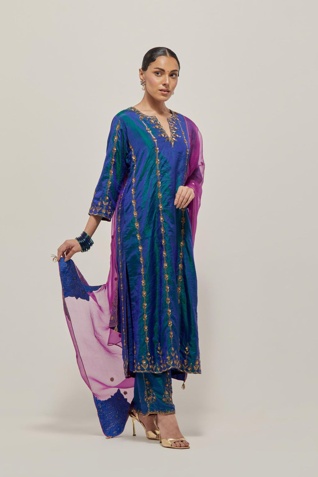 Teal Blue silk straight kurta set with round neck and slit in front. It has hand embroidered zardozi and sequins chhari stripes, all-over and heavier butas at hem, highlighted with beads.