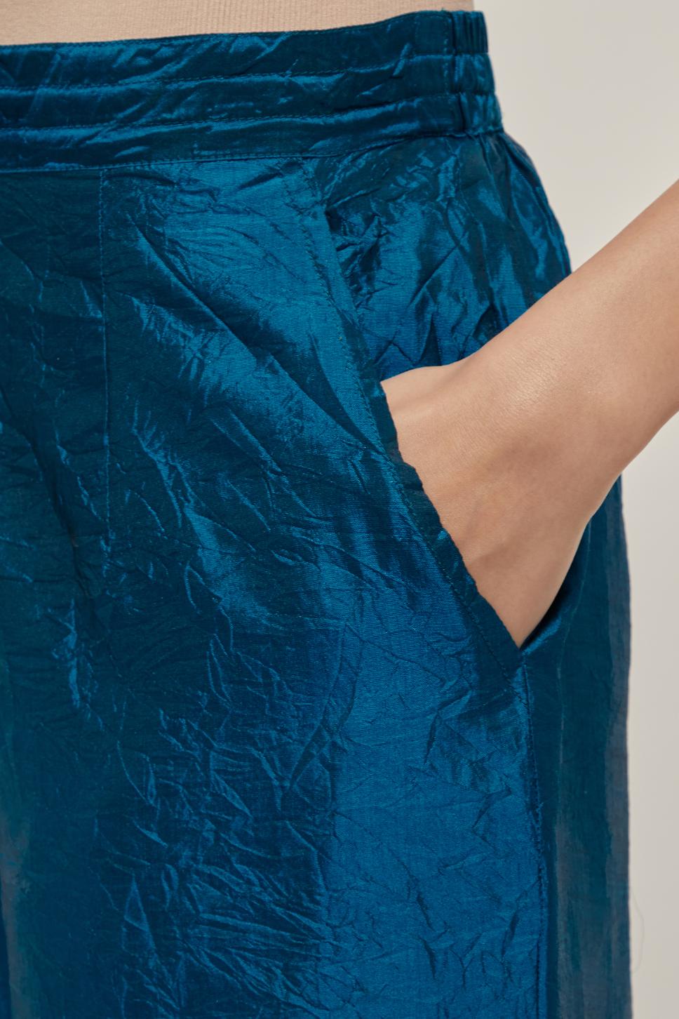 Teal silk pants with side pockets and assorted sequined elephants till mid-calf length.