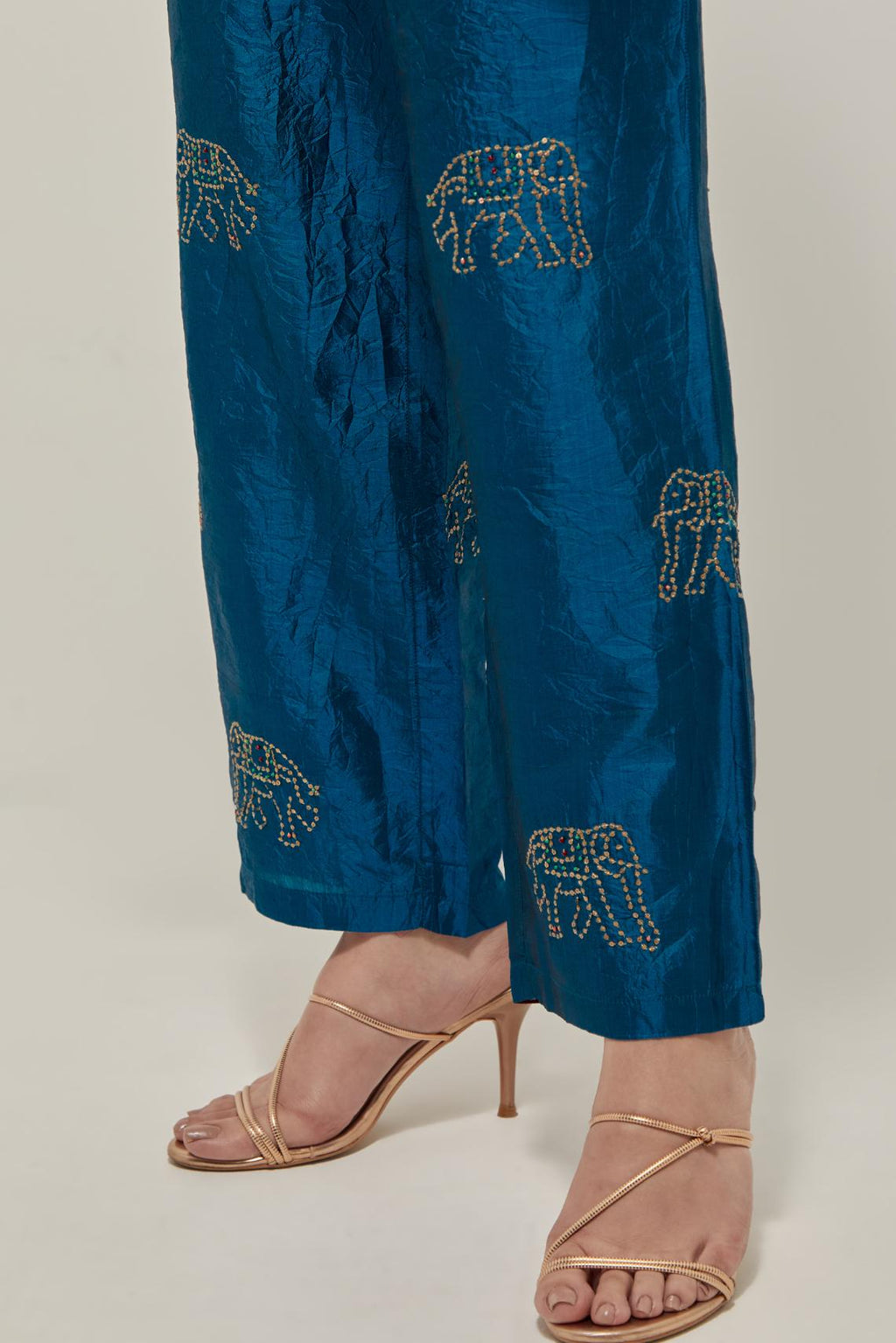 Teal silk pants with side pockets and assorted sequined elephants till mid-calf length.