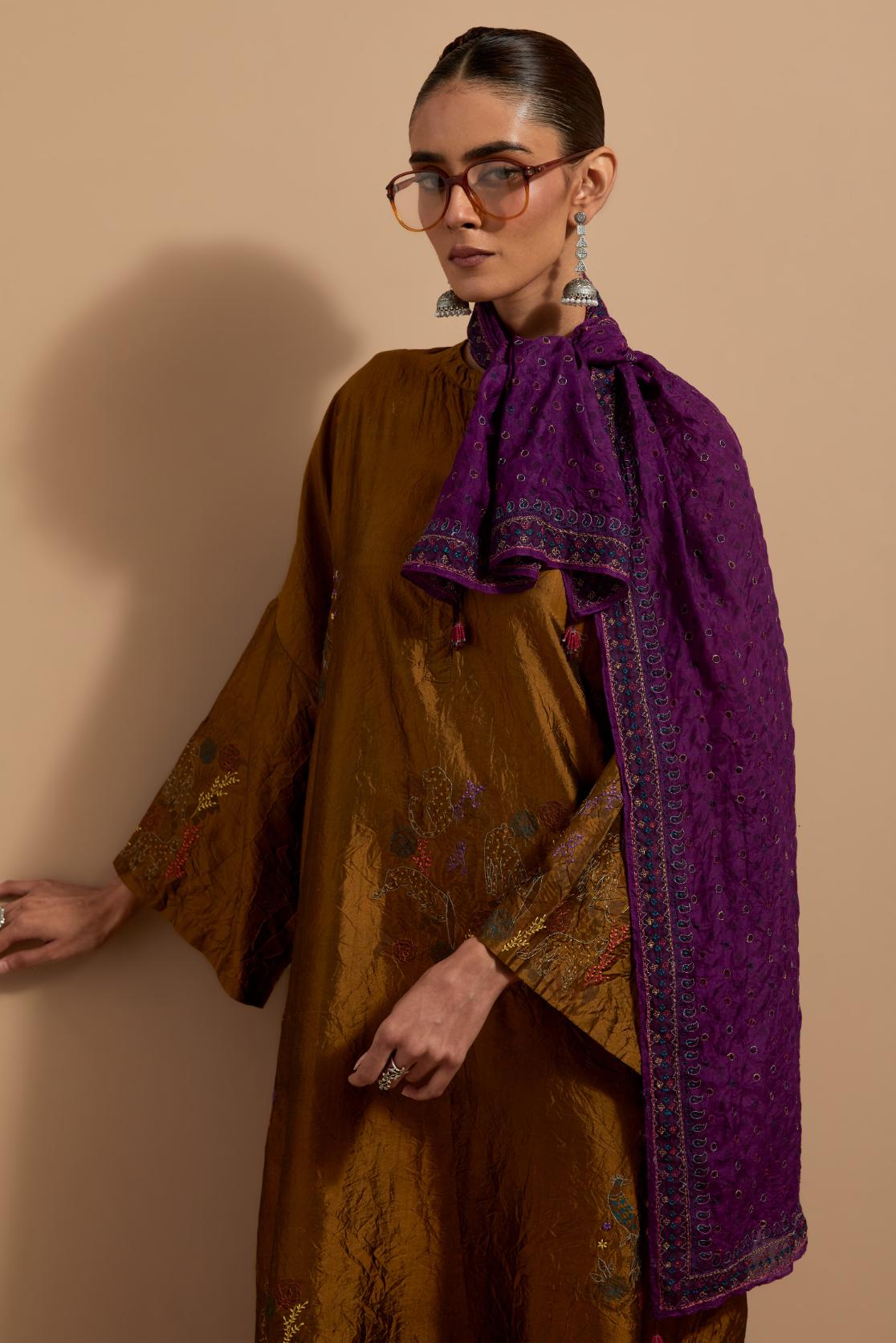 Olive crushed silk hand block printed long kaftan, highlighted with multi colored thread embroidery, paired with Red hand crushed block printed silk stole with quilted embroidery and beaded tassels.