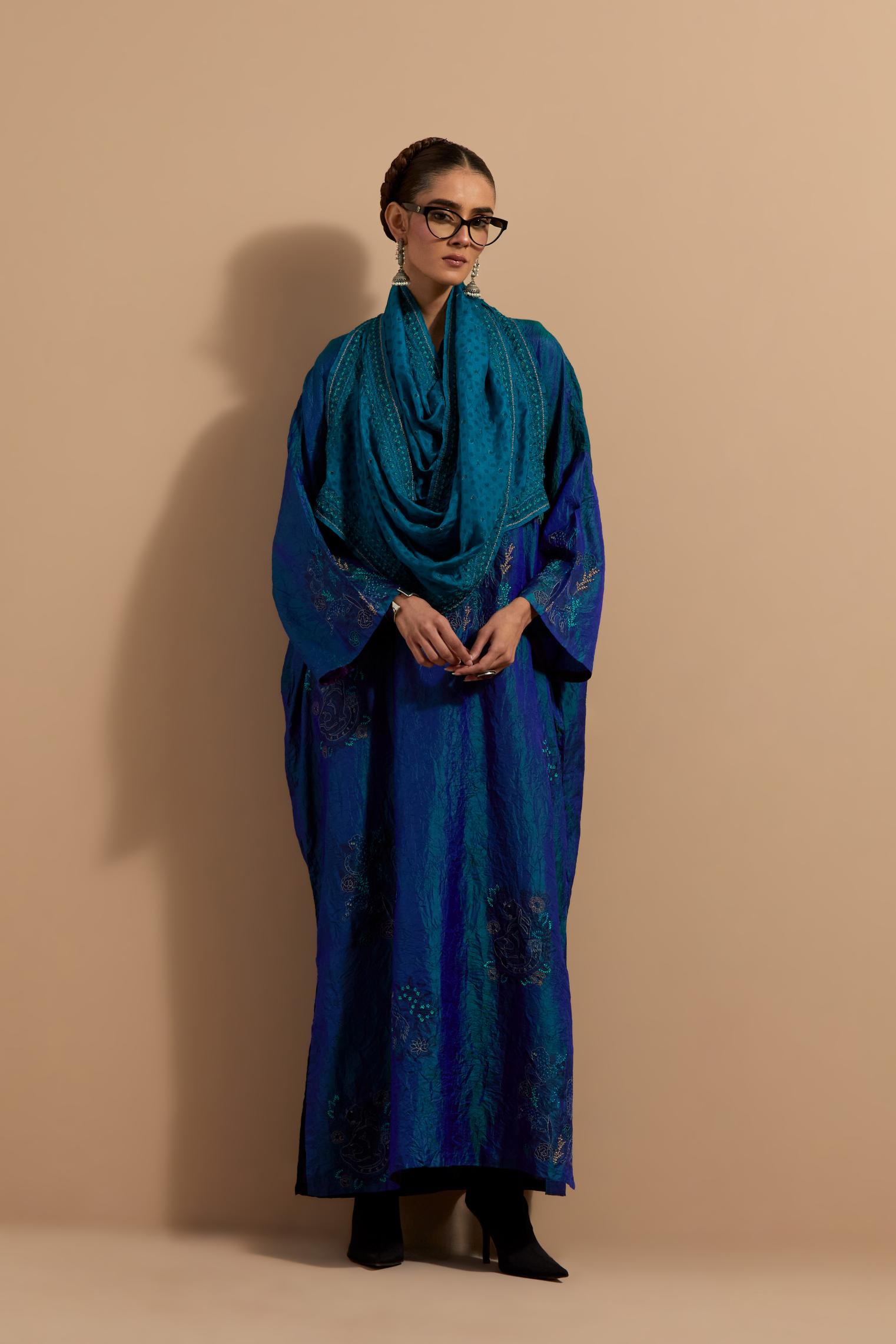 Teal blue crushed silk hand block printed long kaftan, highlighted with multi colored thread embroidery, paired with Red hand crushed block printed silk stole with quilted embroidery and beaded tassels.
