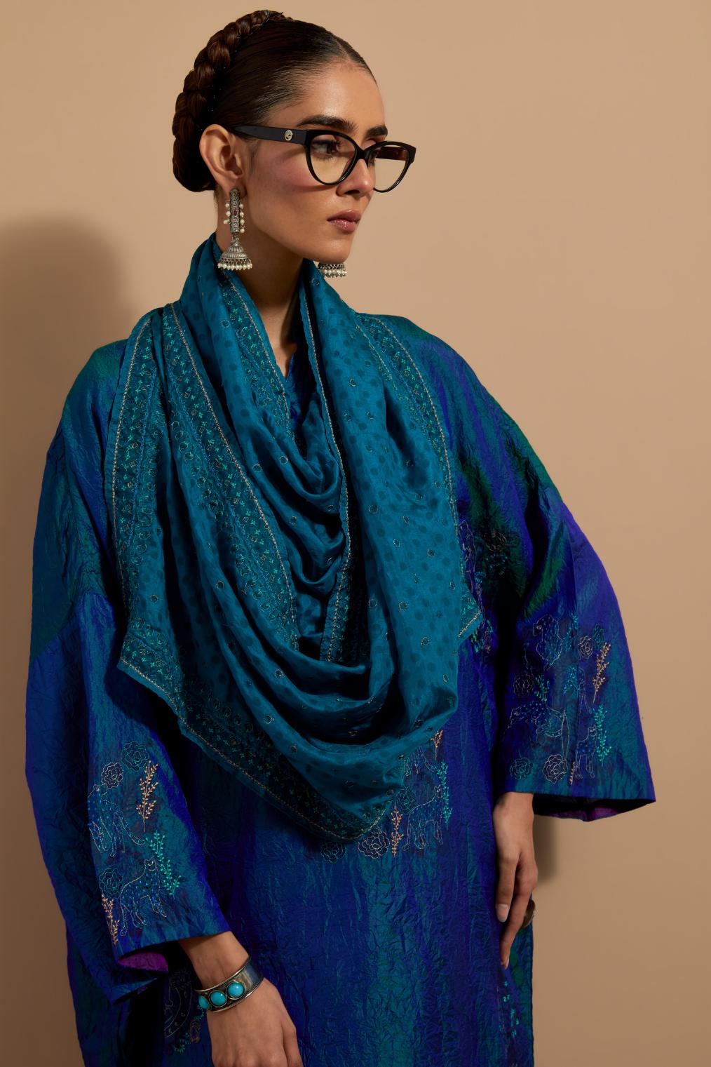 Teal blue crushed silk hand block printed long kaftan, highlighted with multi colored thread embroidery, paired with Red hand crushed block printed silk stole with quilted embroidery and beaded tassels.