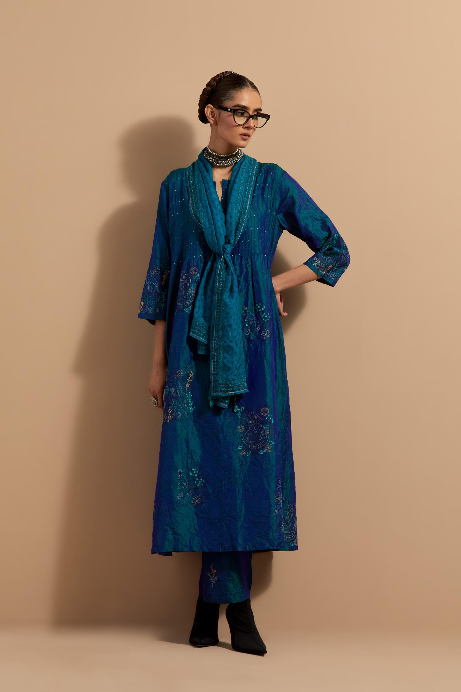 Teal blue crushed silk hand block printed kurta set with pin tucks at yoke, highlighted with multi colored thread embroidery.