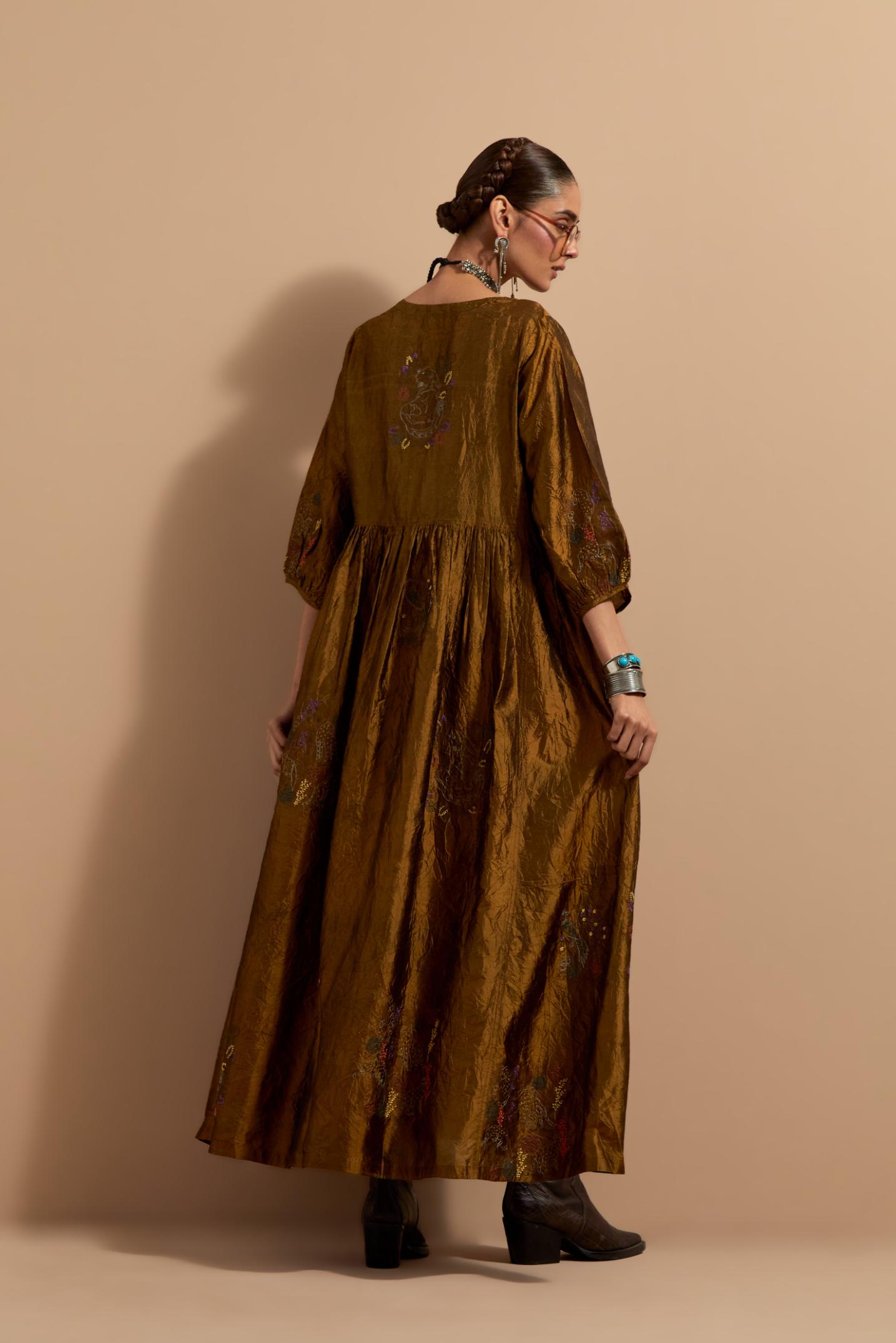Olive crushed silk hand block printed long dress, highlighted with multi colored thread embroidery, paired with Purple hand crushed block printed silk stole with quilted embroidery and beaded tassels.