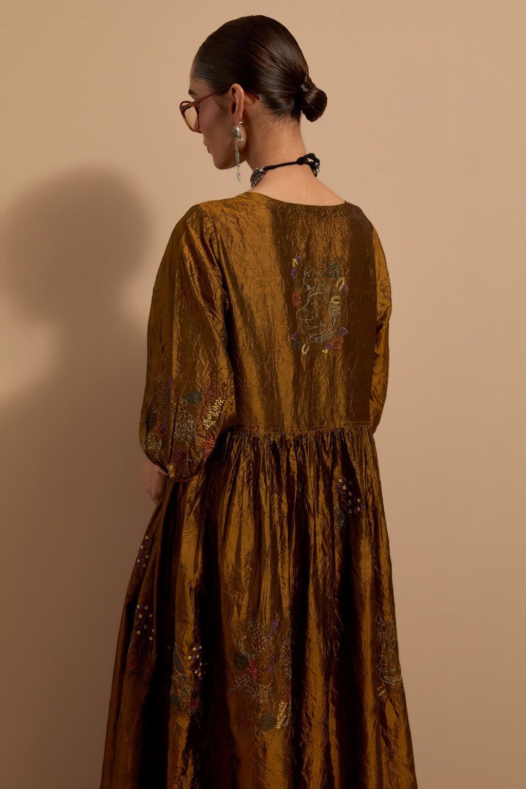 Olive crushed silk hand block printed long dress, highlighted with multi colored thread embroidery, paired with Purple hand crushed block printed silk stole with quilted embroidery and beaded tassels.