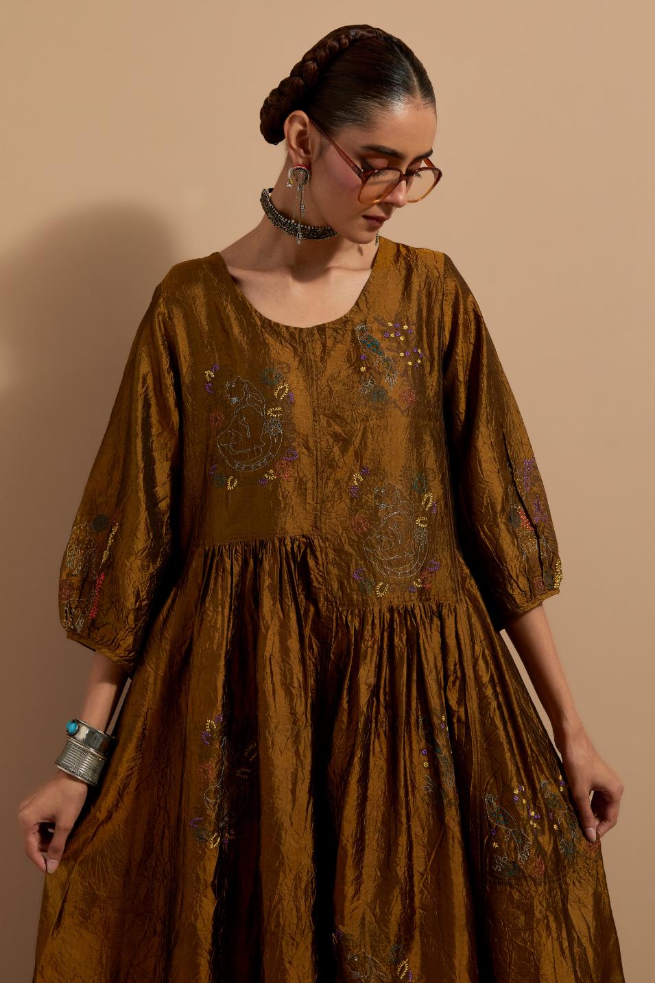 Olive crushed silk hand block printed long dress, highlighted with multi colored thread embroidery, paired with Purple hand crushed block printed silk stole with quilted embroidery and beaded tassels.