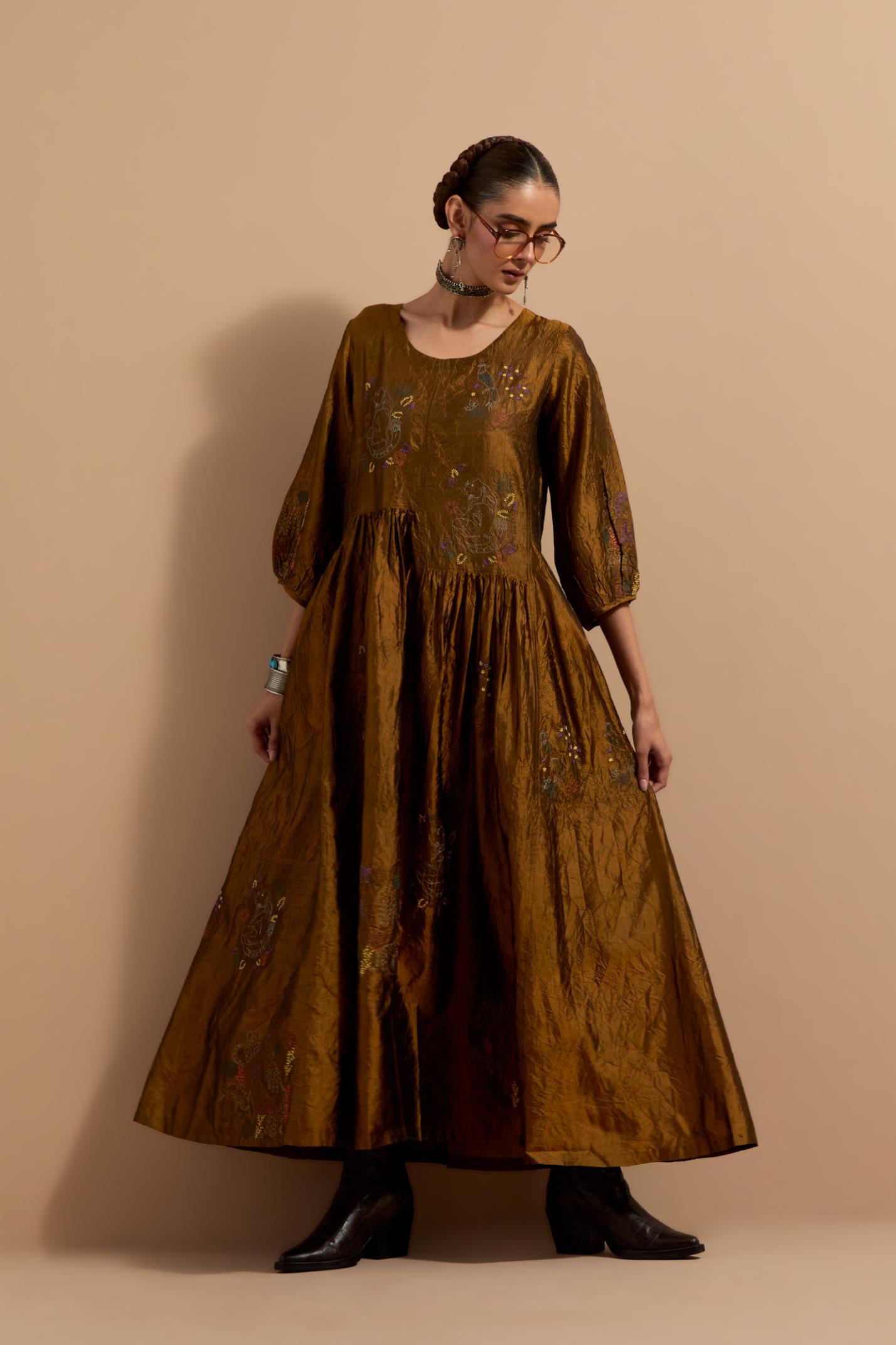 Olive crushed silk hand block printed long dress, highlighted with multi colored thread embroidery, paired with Purple hand crushed block printed silk stole with quilted embroidery and beaded tassels.
