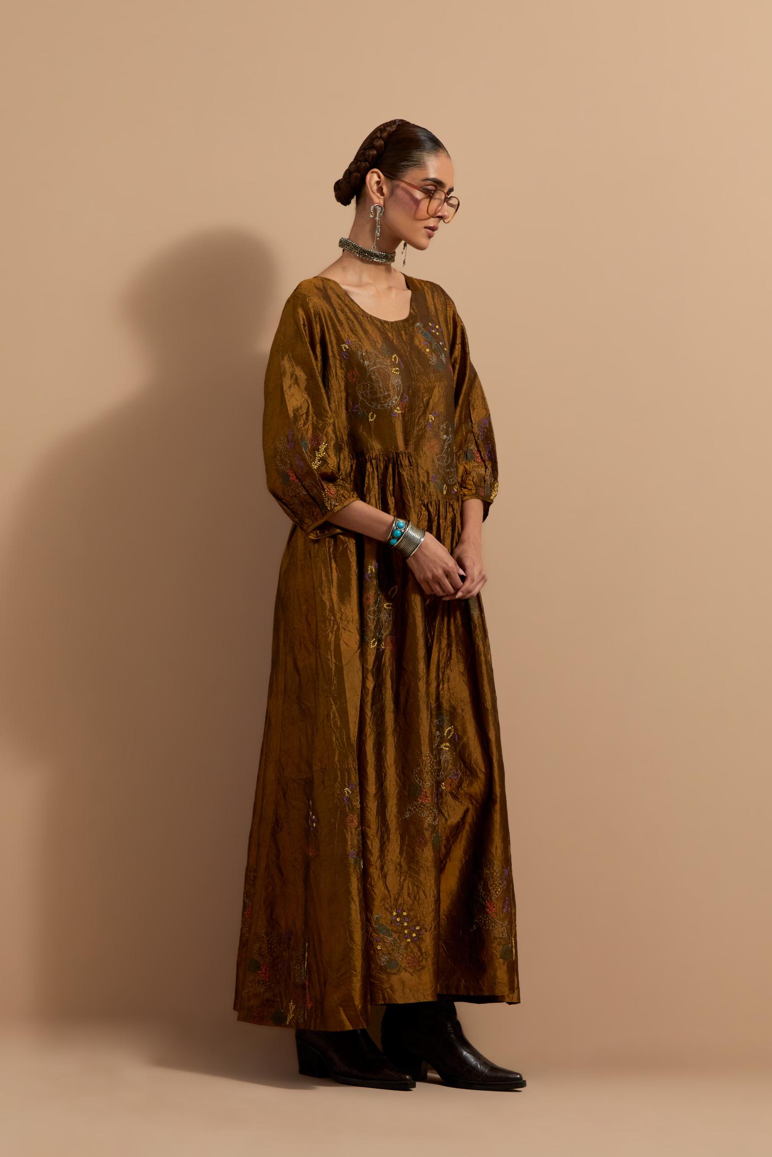 Olive crushed silk hand block printed long dress, highlighted with multi colored thread embroidery, paired with Purple hand crushed block printed silk stole with quilted embroidery and beaded tassels.