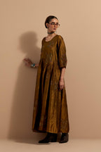 Olive crushed silk hand block printed long dress, highlighted with multi colored thread embroidery, paired with Purple hand crushed block printed silk stole with quilted embroidery and beaded tassels.
