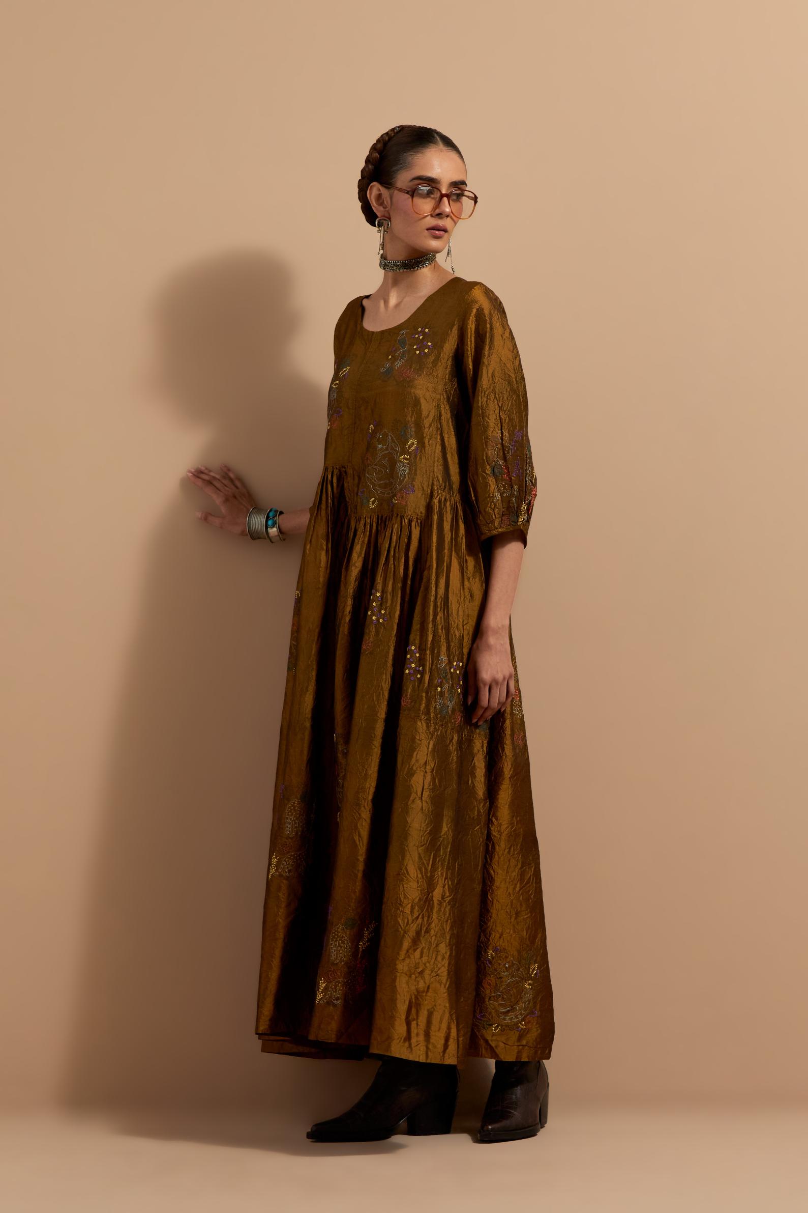 Olive crushed silk hand block printed long dress, highlighted with multi colored thread embroidery, paired with Purple hand crushed block printed silk stole with quilted embroidery and beaded tassels.