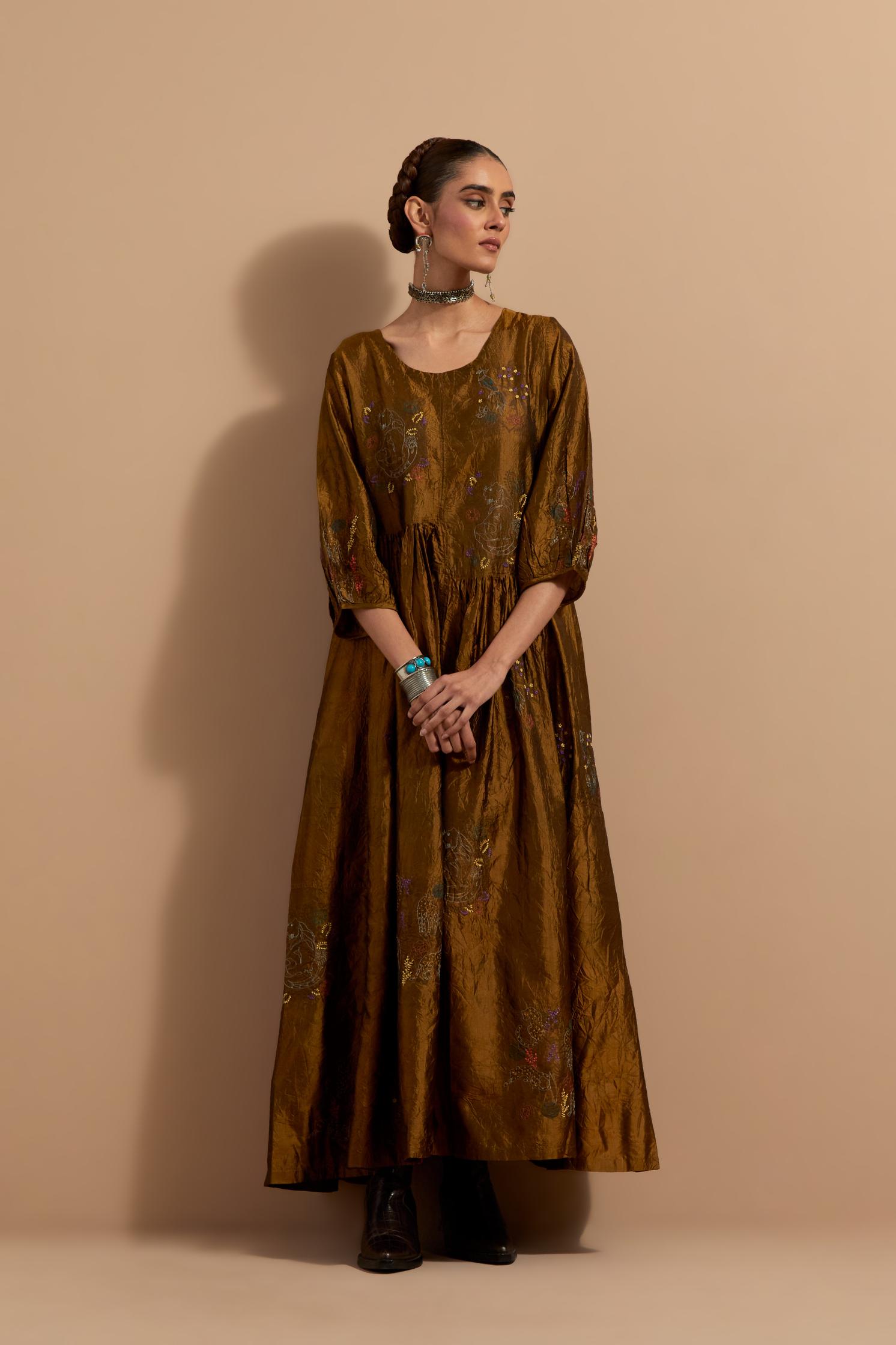 Olive crushed silk hand block printed long dress, highlighted with multi colored thread embroidery, paired with Purple hand crushed block printed silk stole with quilted embroidery and beaded tassels.
