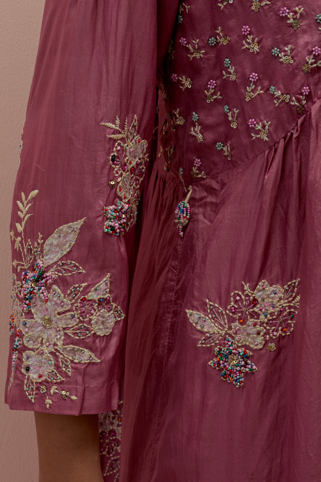 Salmon pink silk kurta dress set with delicate embroidered flowers and hand block printed appliqué motifs, highlighted with sequins and multi-colored beads.