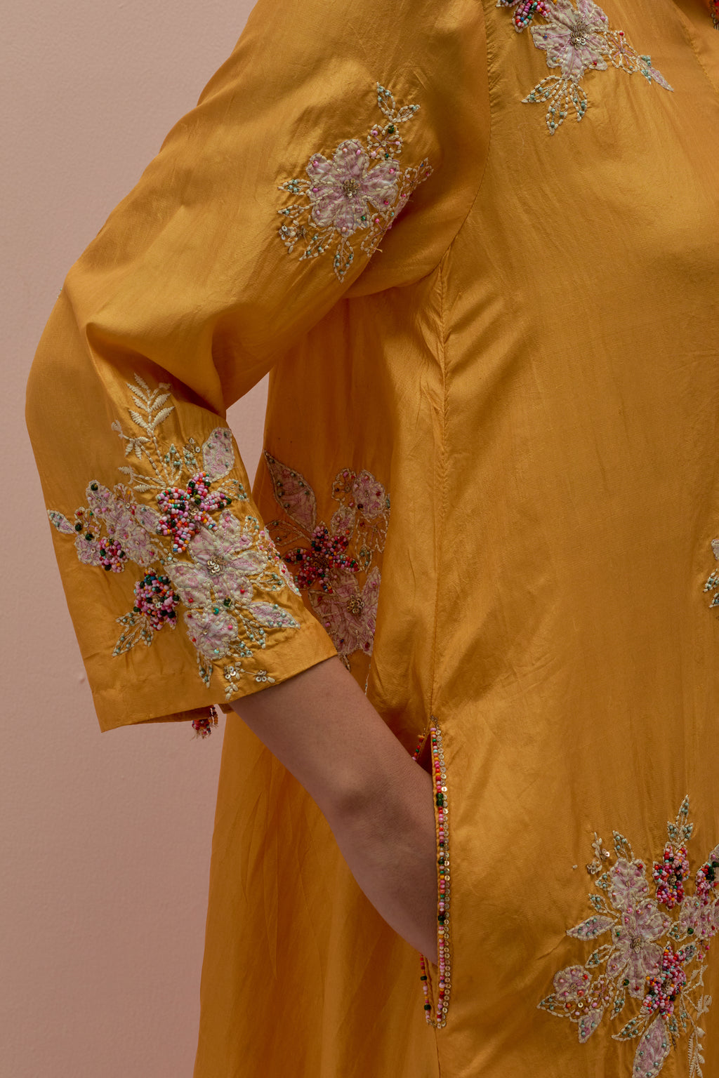 Amber silk short shirt-kurta set with all-over appliqué flowers, highlighted with sequins and multi-colored beads.