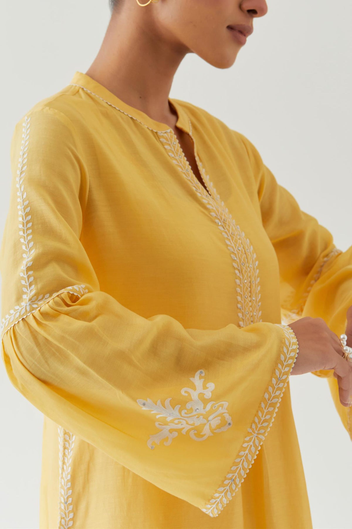 Yellow silk chanderi straight kurta set with long bell sleeves, highlighted with off white thread embroidery.