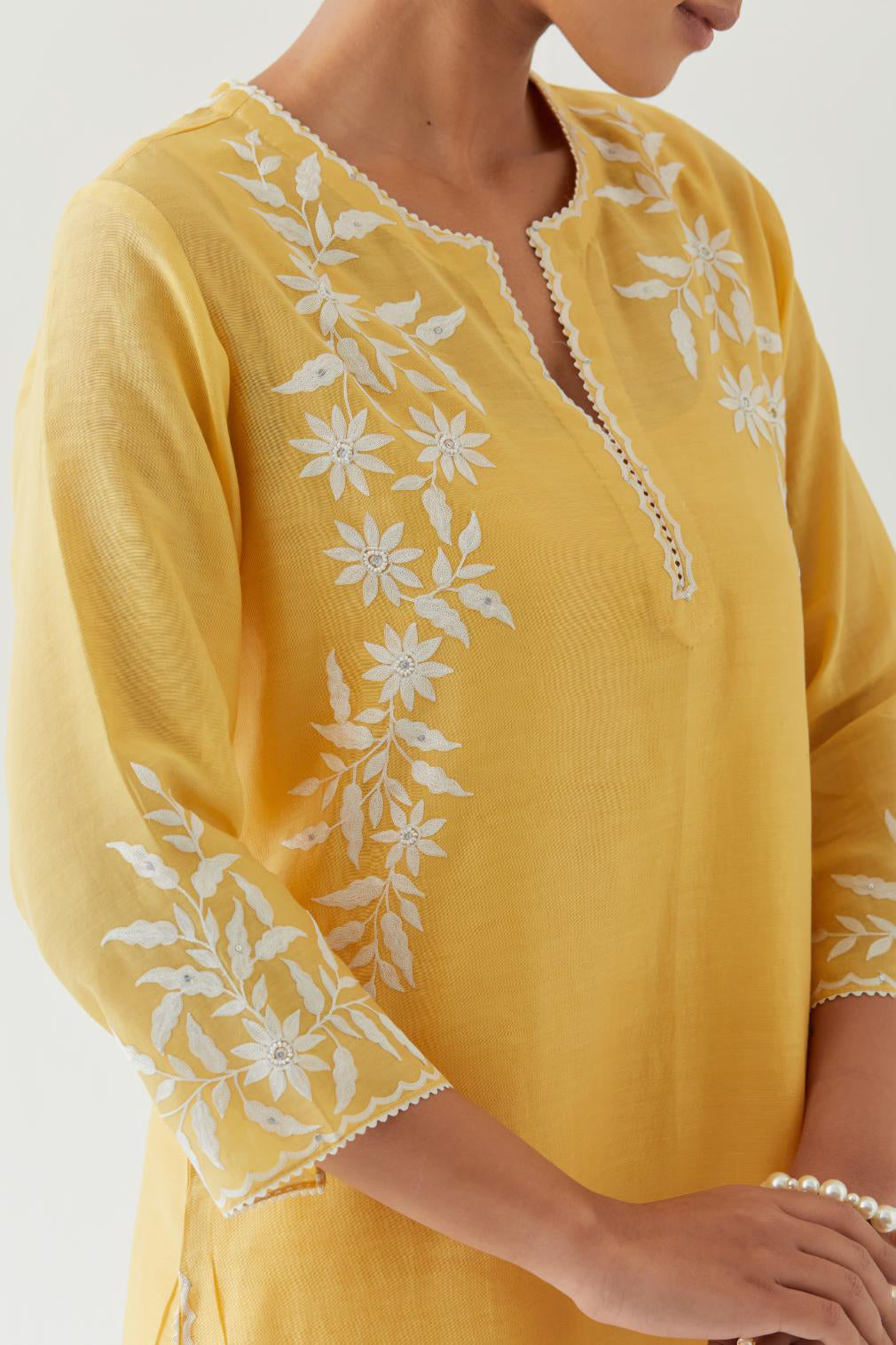 Yellow silk chanderi straight kurta set highlighted with off white thread embroidery.