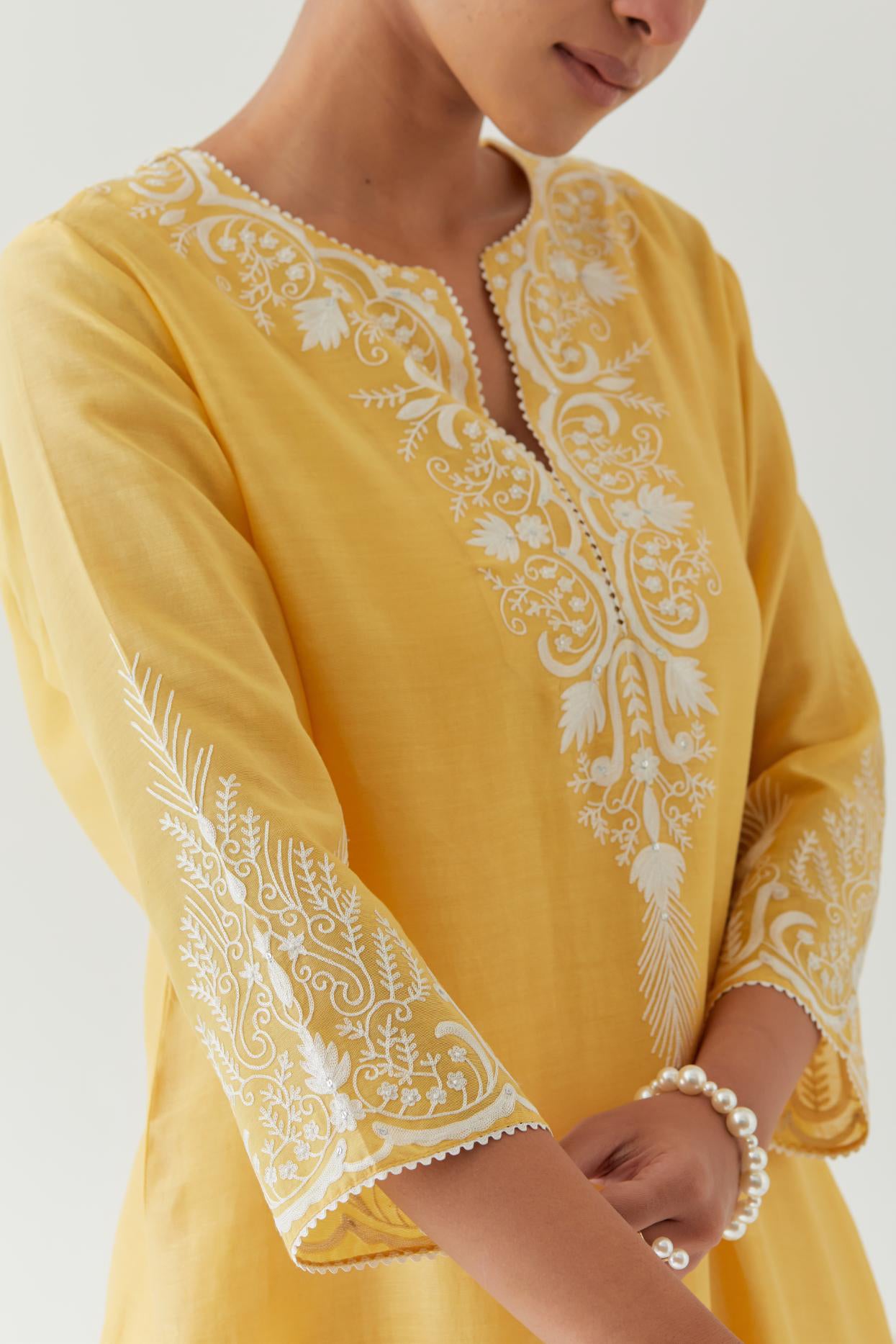 Yellow silk chanderi straight kurta set highlighted with off white thread embroidery.