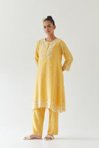 Yellow silk chanderi short A-line kurta set highlighted with off white thread embroidery.
