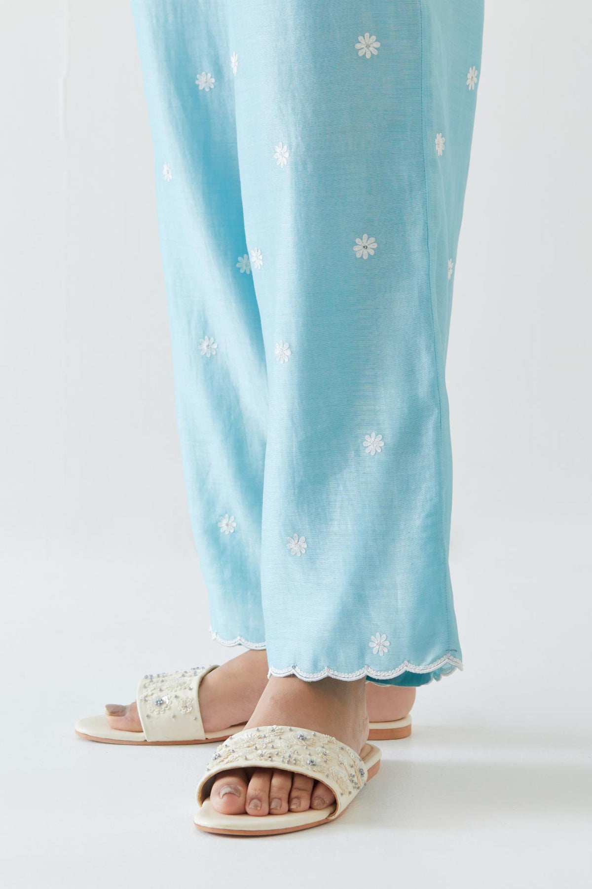 Blue silk chanderi straight pants with off white thread embroidery and scalloped edges at hem.
